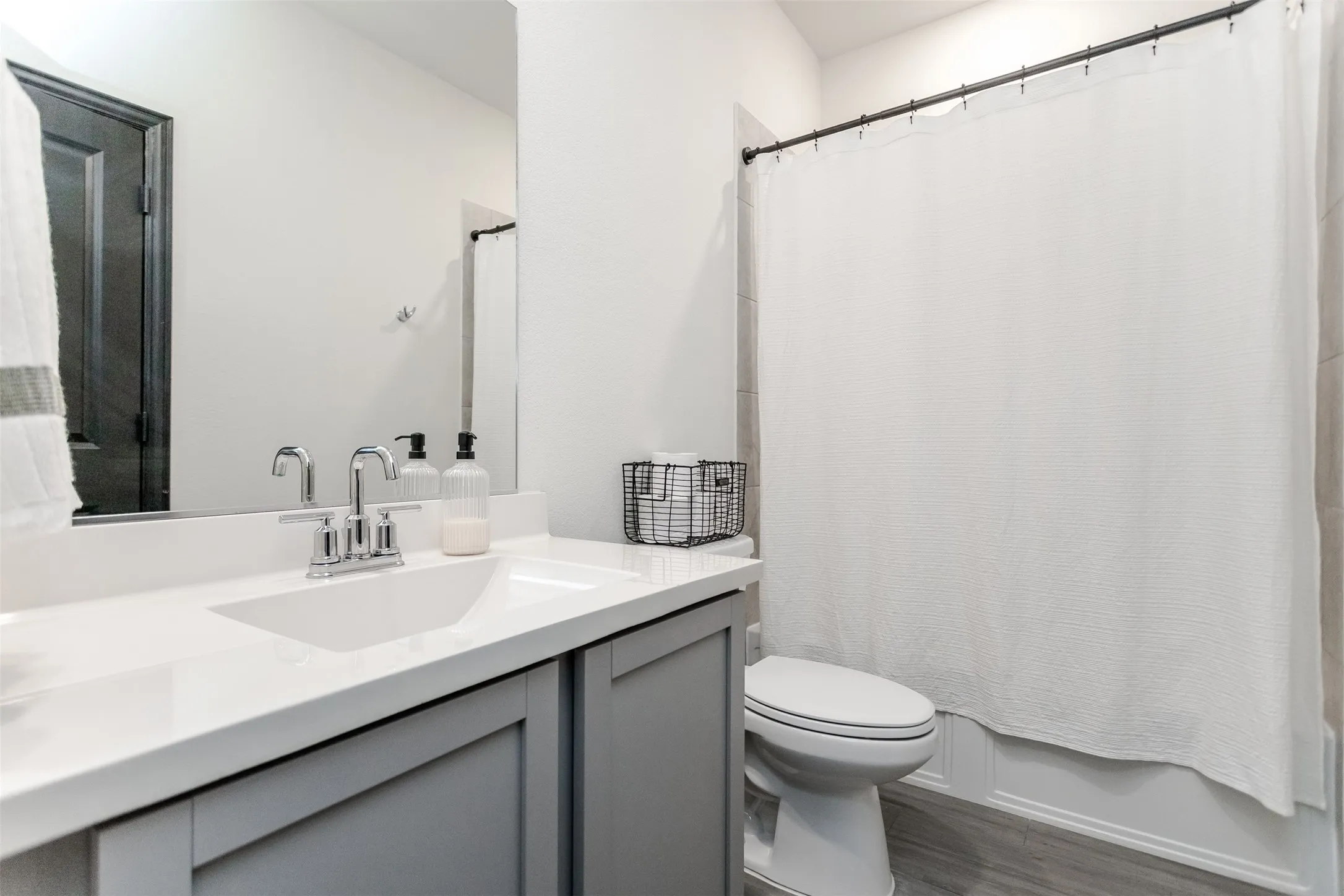 White vanity with an integrated sink and chrome faucet, gray paneled cabinetry, and a full-width mirror
