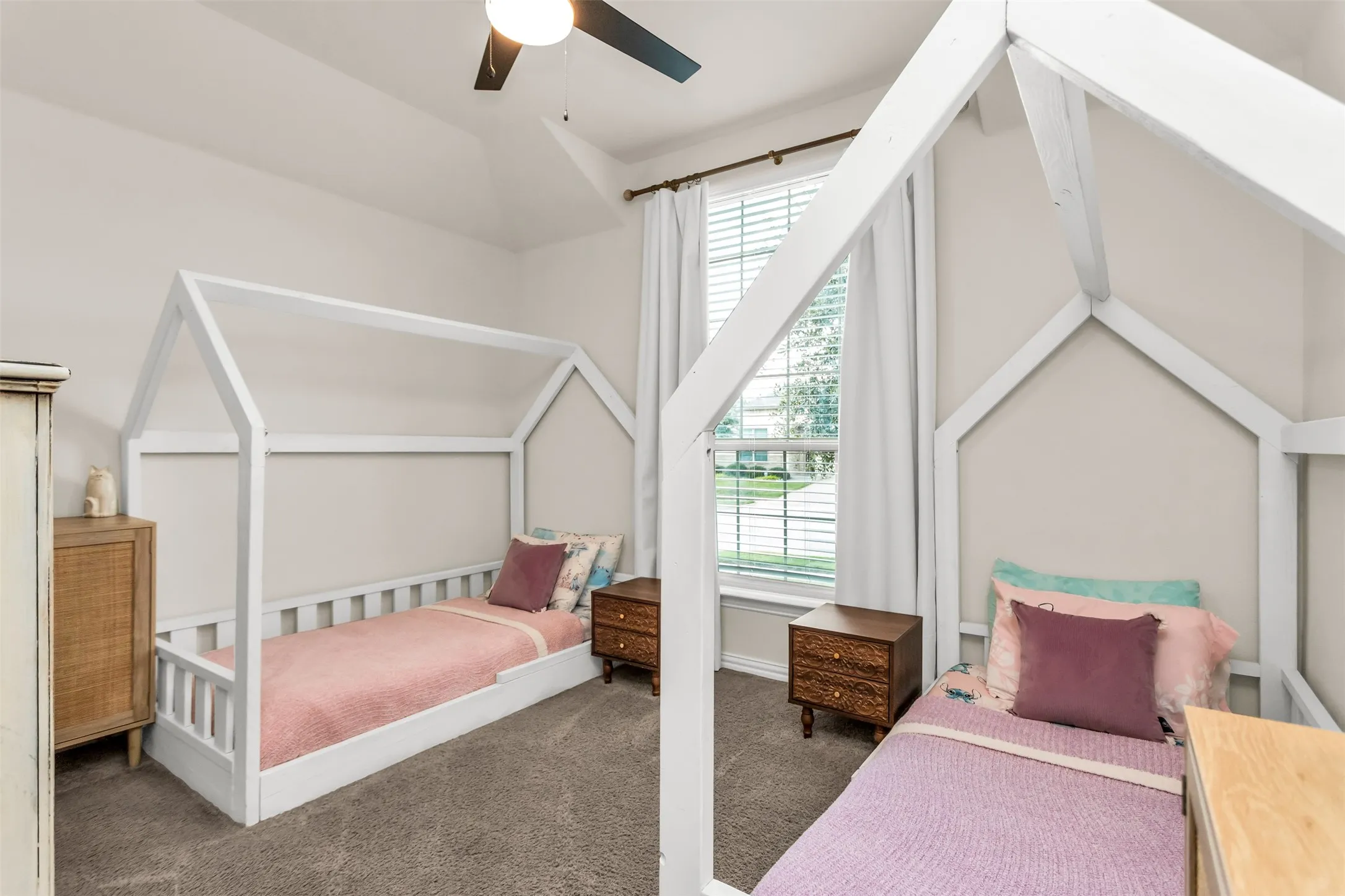 Room featuring a vaulted ceiling with a ceiling fan, carpet flooring, and a large window with blinds and curtains