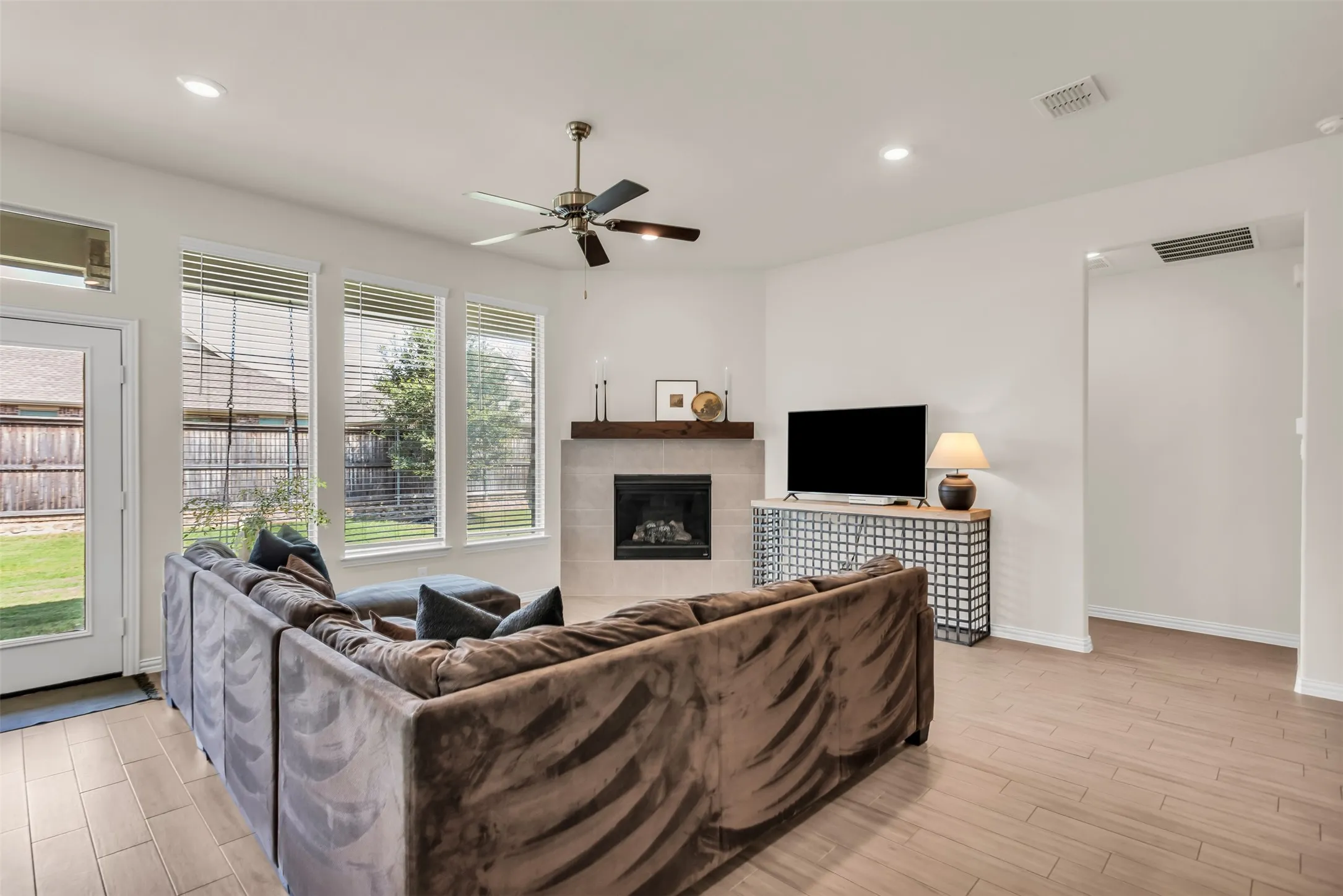 Recessed lighting, ceiling fan, wood-finish flooring, fireplace with a wood mantle, and multiple windows