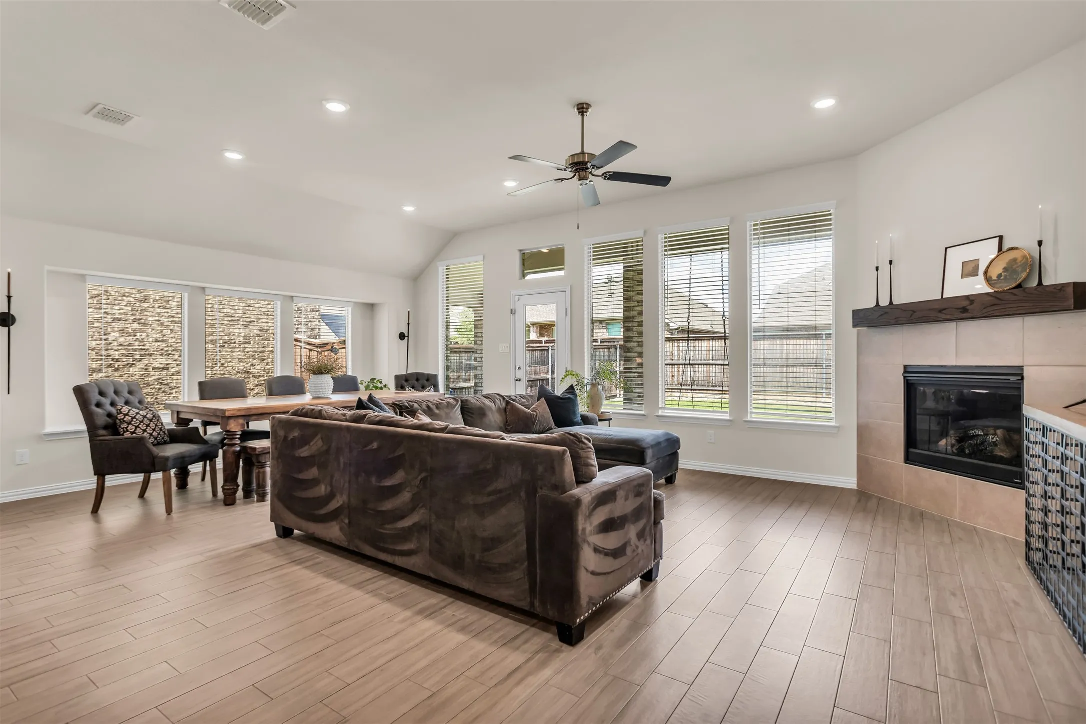 Open-concept living space with wood-finish flooring, recessed lighting, and a vaulted ceiling