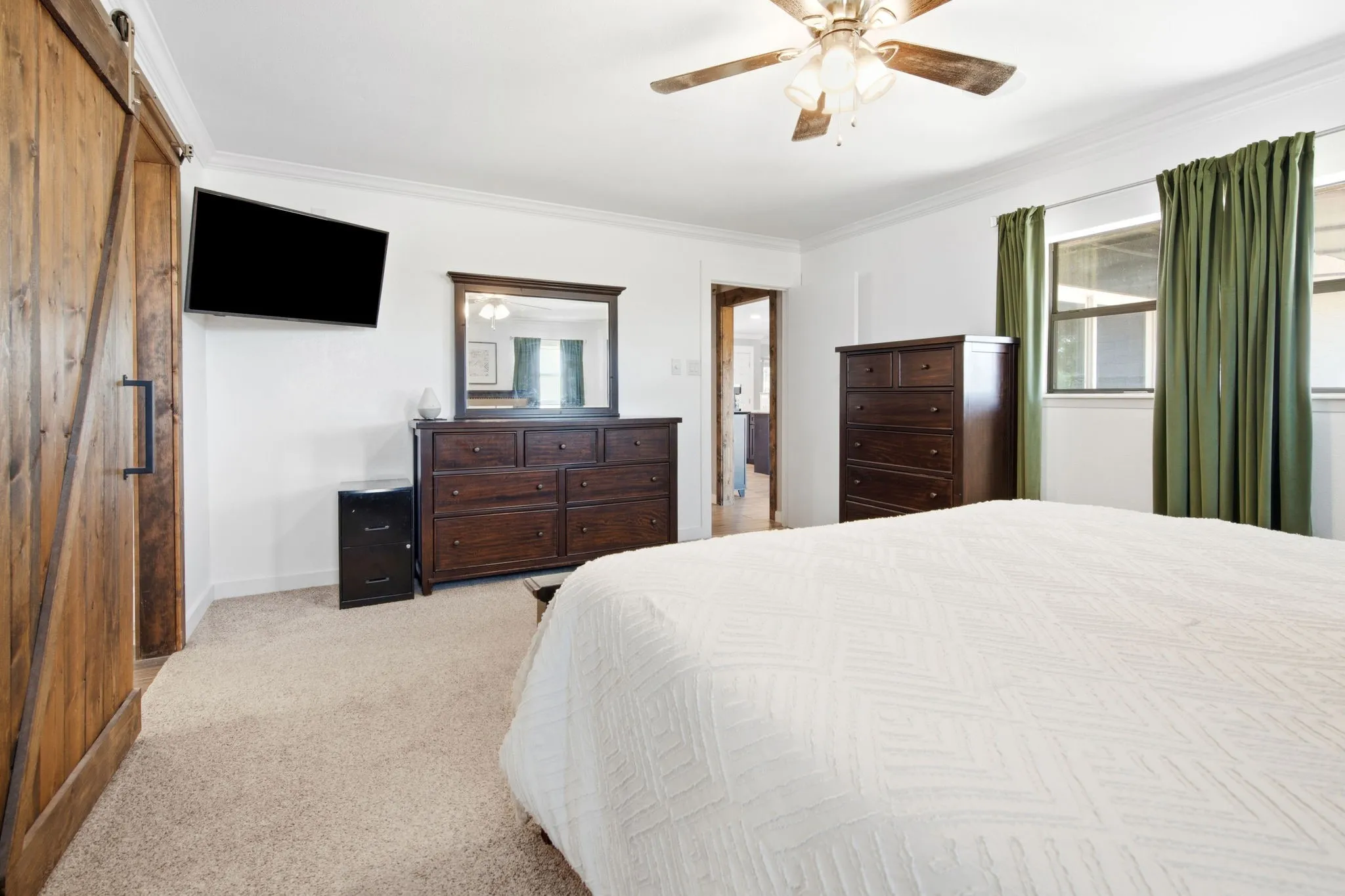 Carpeted flooring, on suite bathroom, crown molding, and a wood-finish barn door