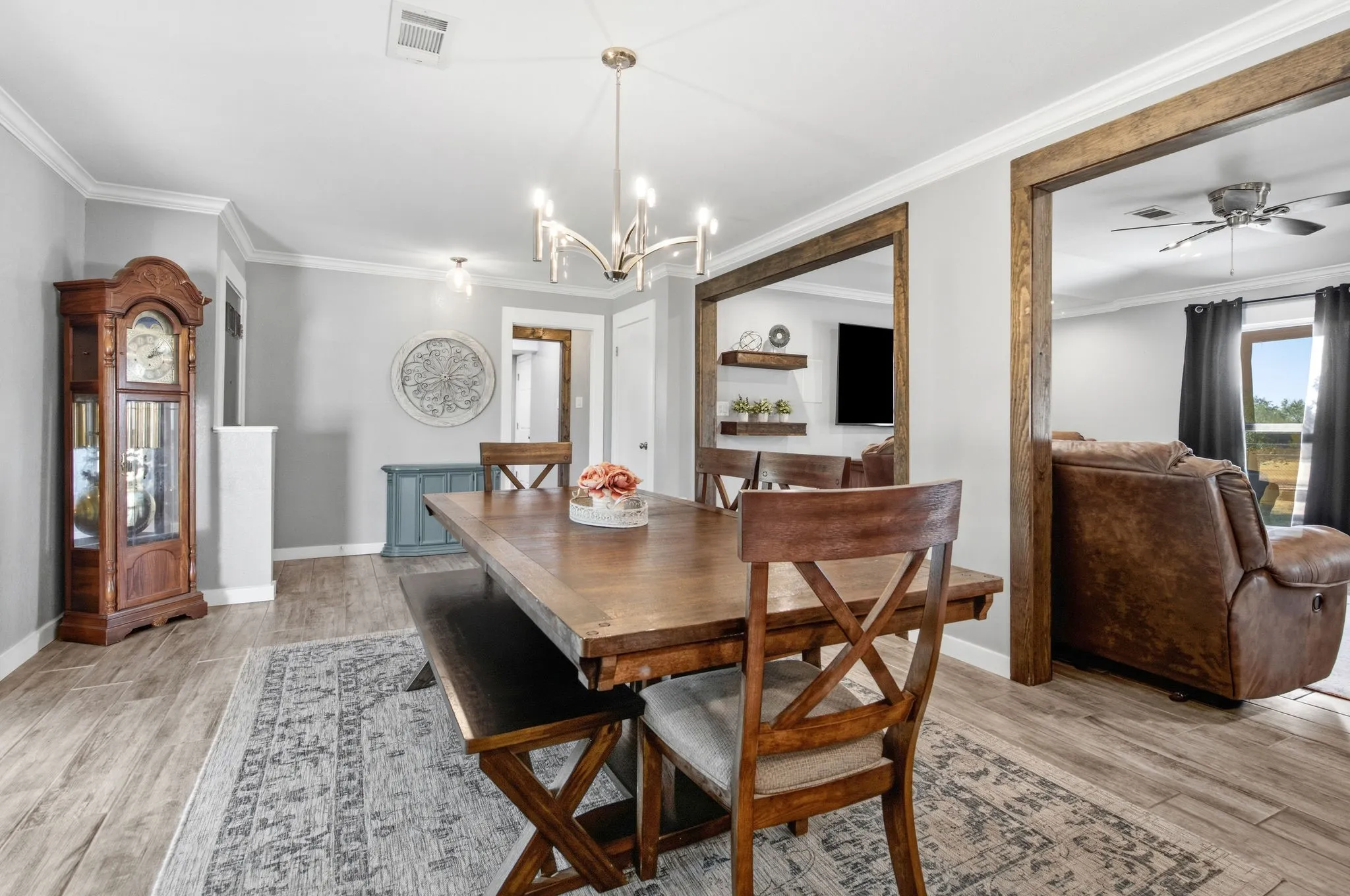 Wood-finish flooring throughout, modern chandelier, crown molding, and framed openings