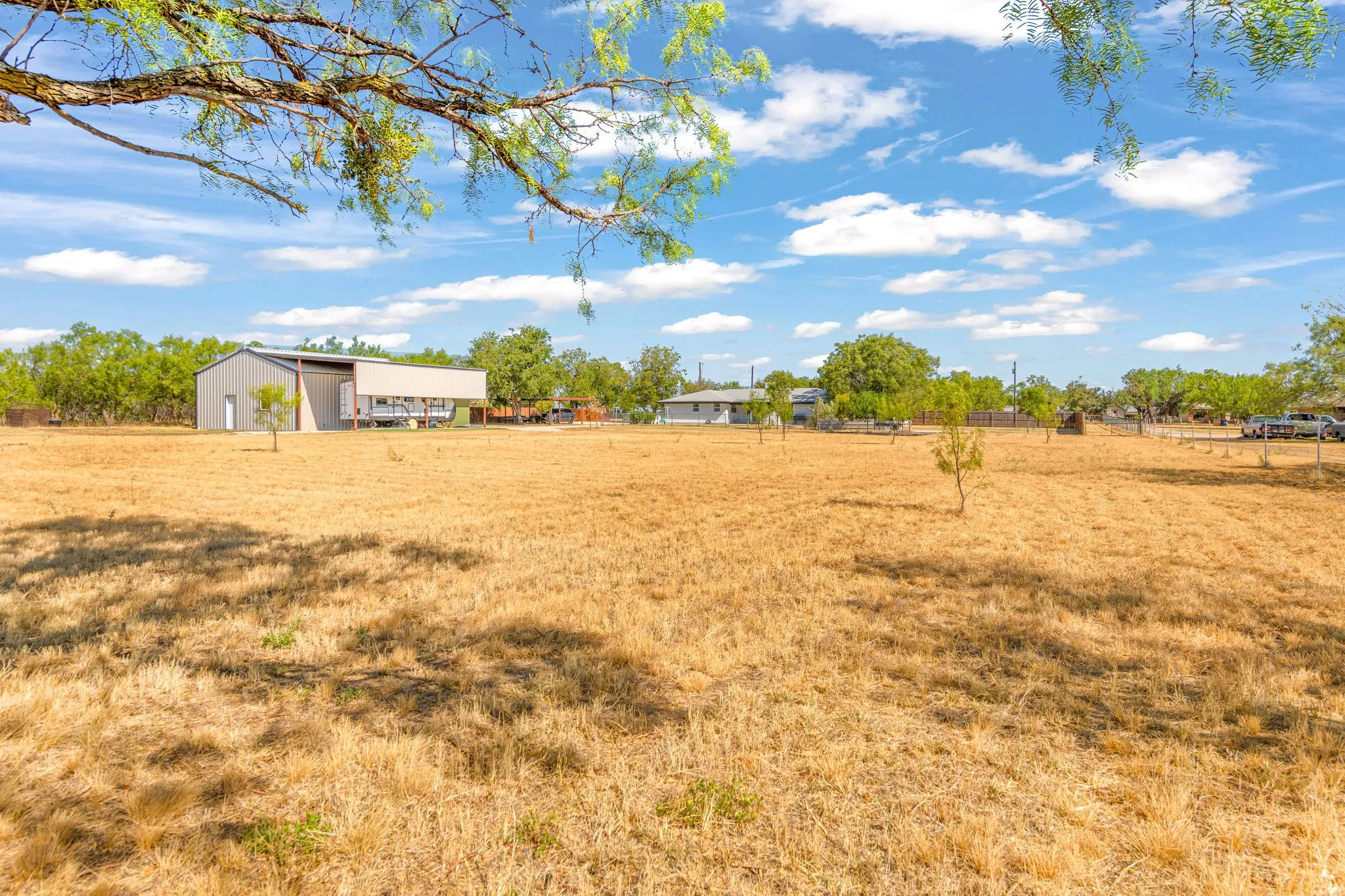 Expansive outdoor space featuring a workshop with a covered porch and mature trees