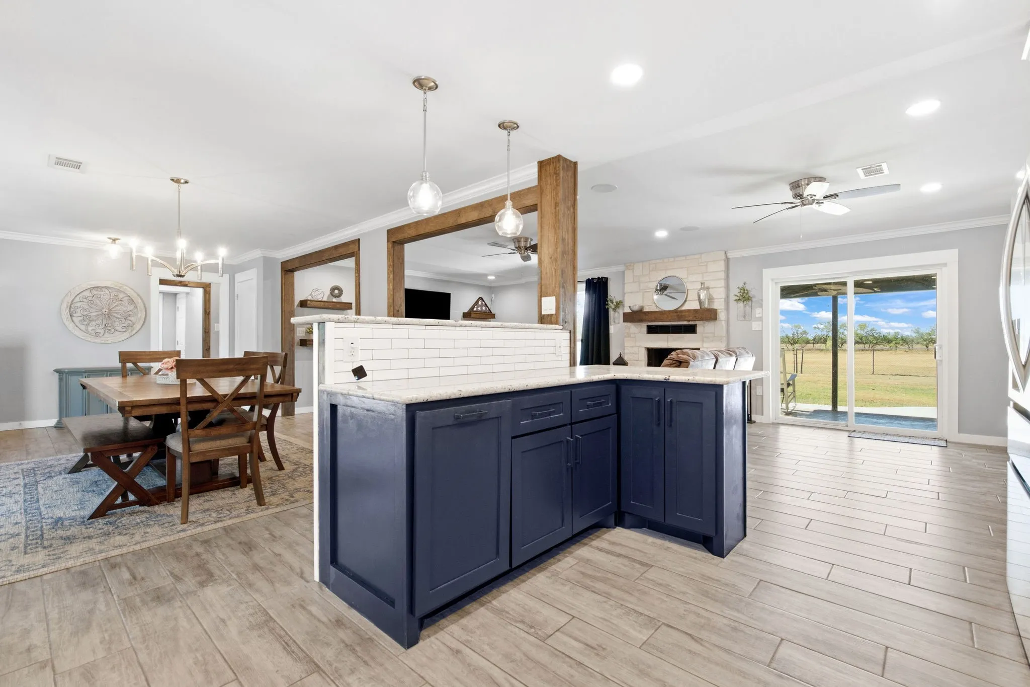 Open-concept interior featuring wood-finish flooring, a functional kitchen island with pendant lighting looking out to a private back yard