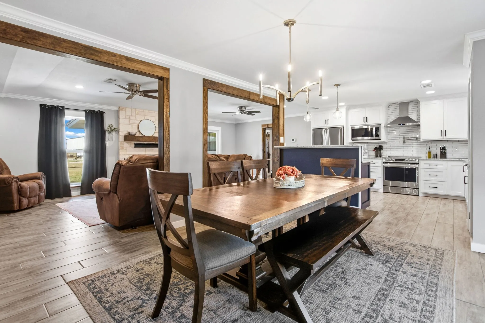 Dining area featuring wood-finish flooring, a contemporary chandelier, looking into the living room with a stone fireplace