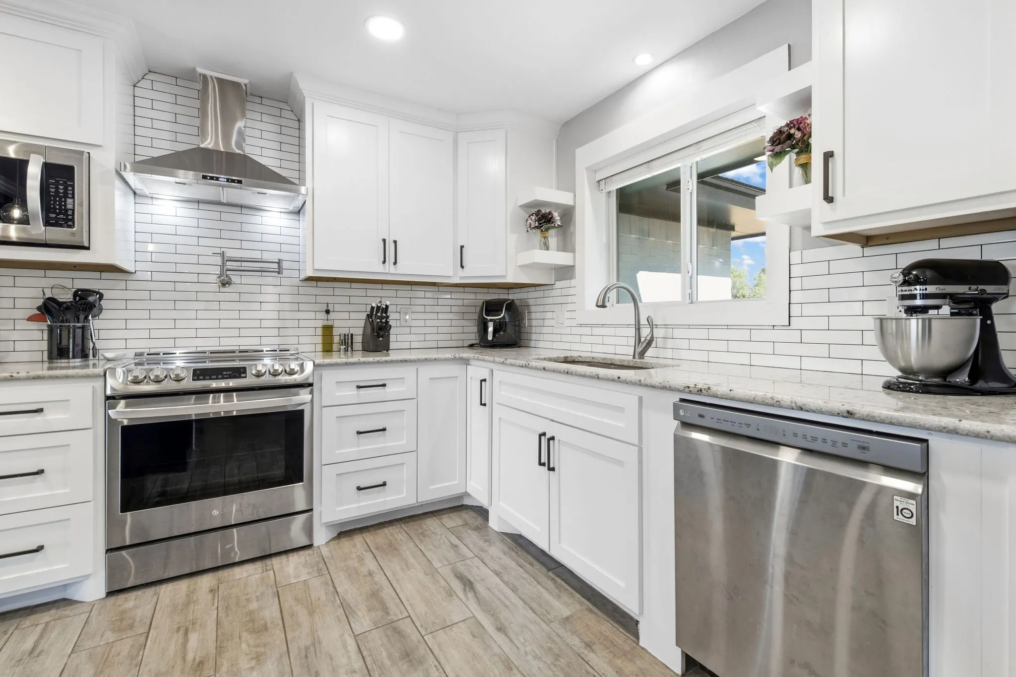 Kitchen with stainless steel appliances, subway tile backsplash, light-toned wood-finish flooring, and recessed lighting
