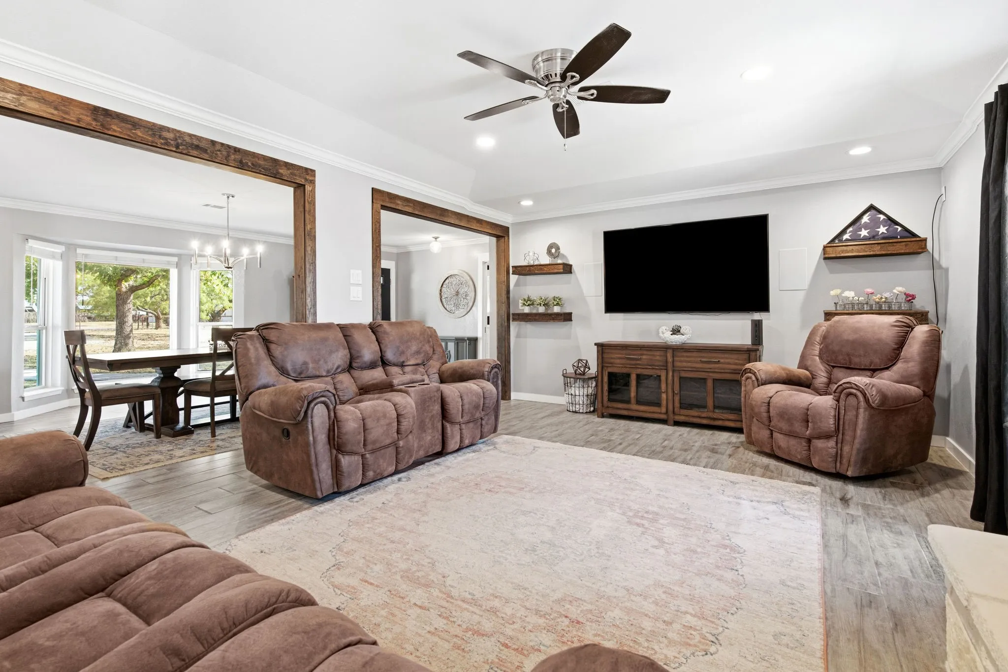 Living room with wood-finish flooring throughout, recessed lighting, and crown molding