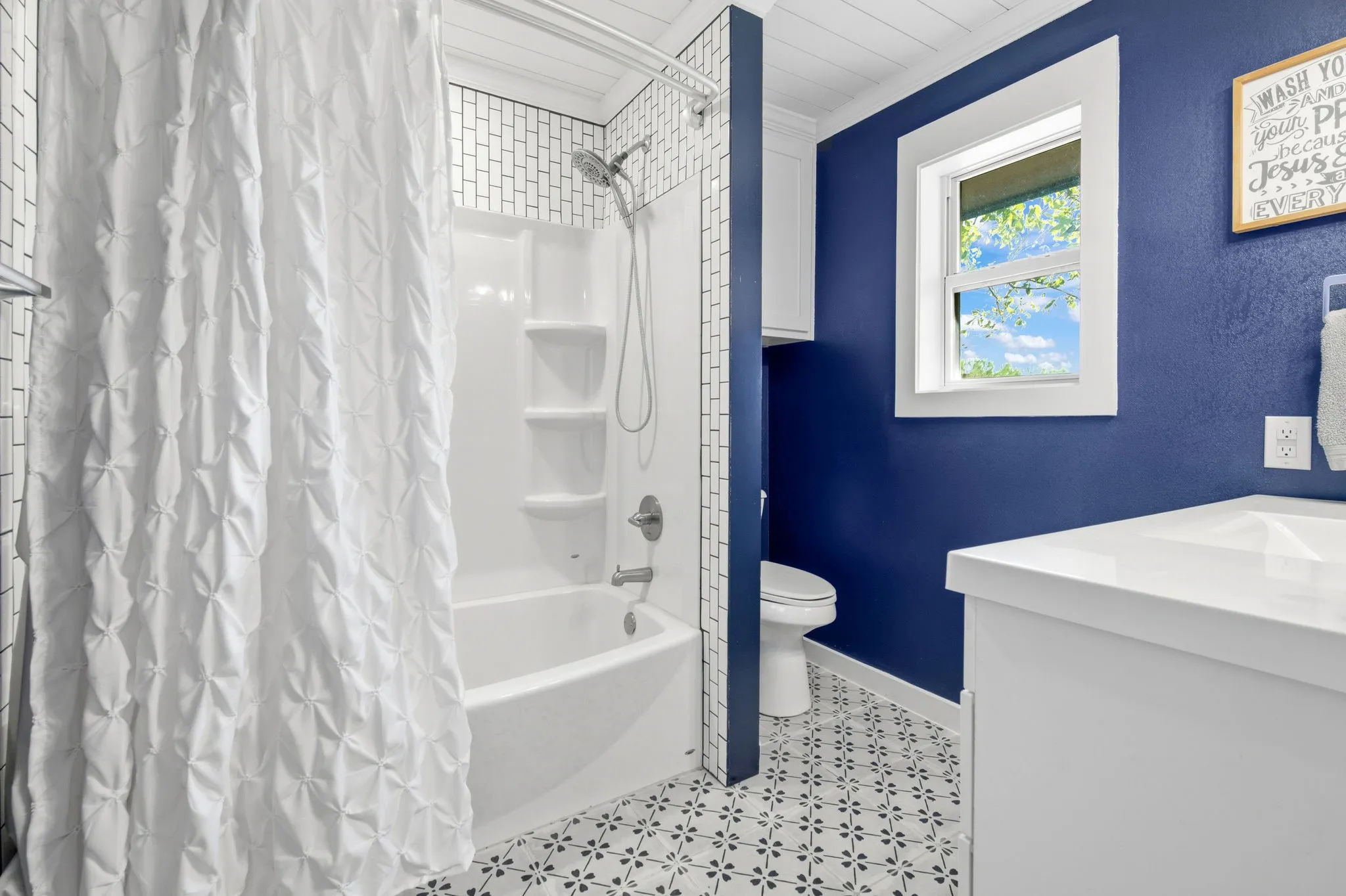 White-tiled shower with a built-in tub and shelving, complemented by a vanity with an integrated sink