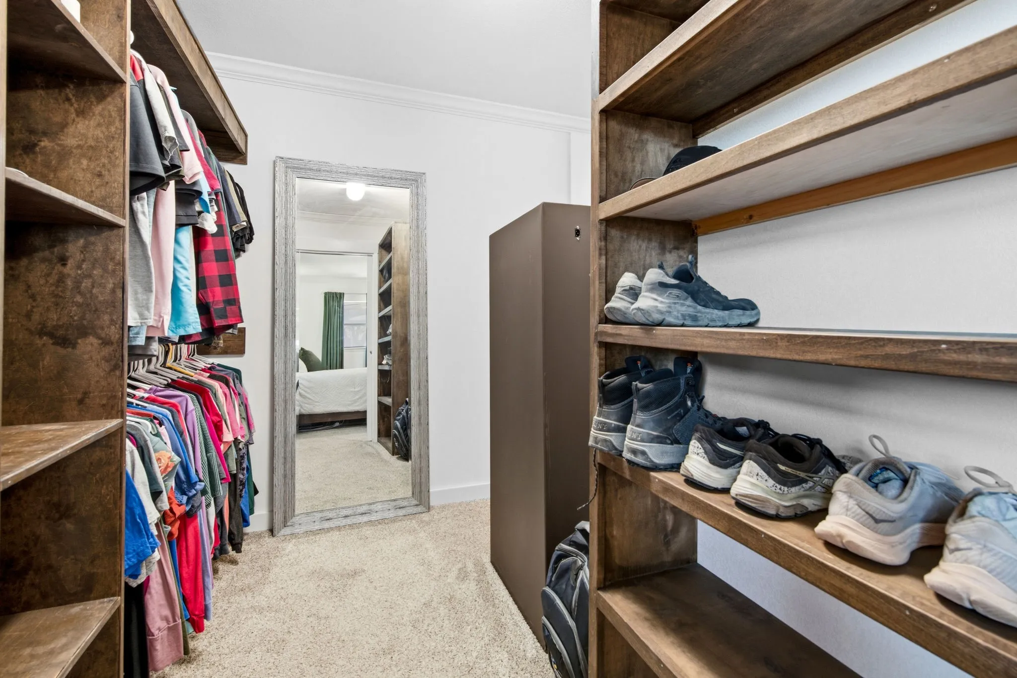 Custom built-in wood shelving, hanging racks, and carpeted flooring