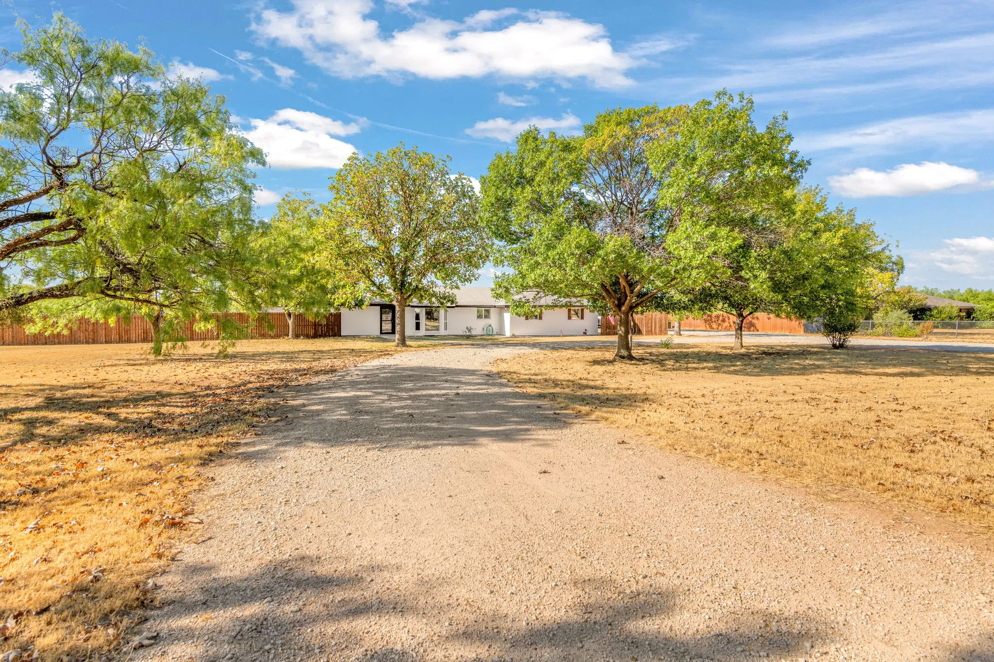 Inviting driveway leading to a single-story residence with a white exterior