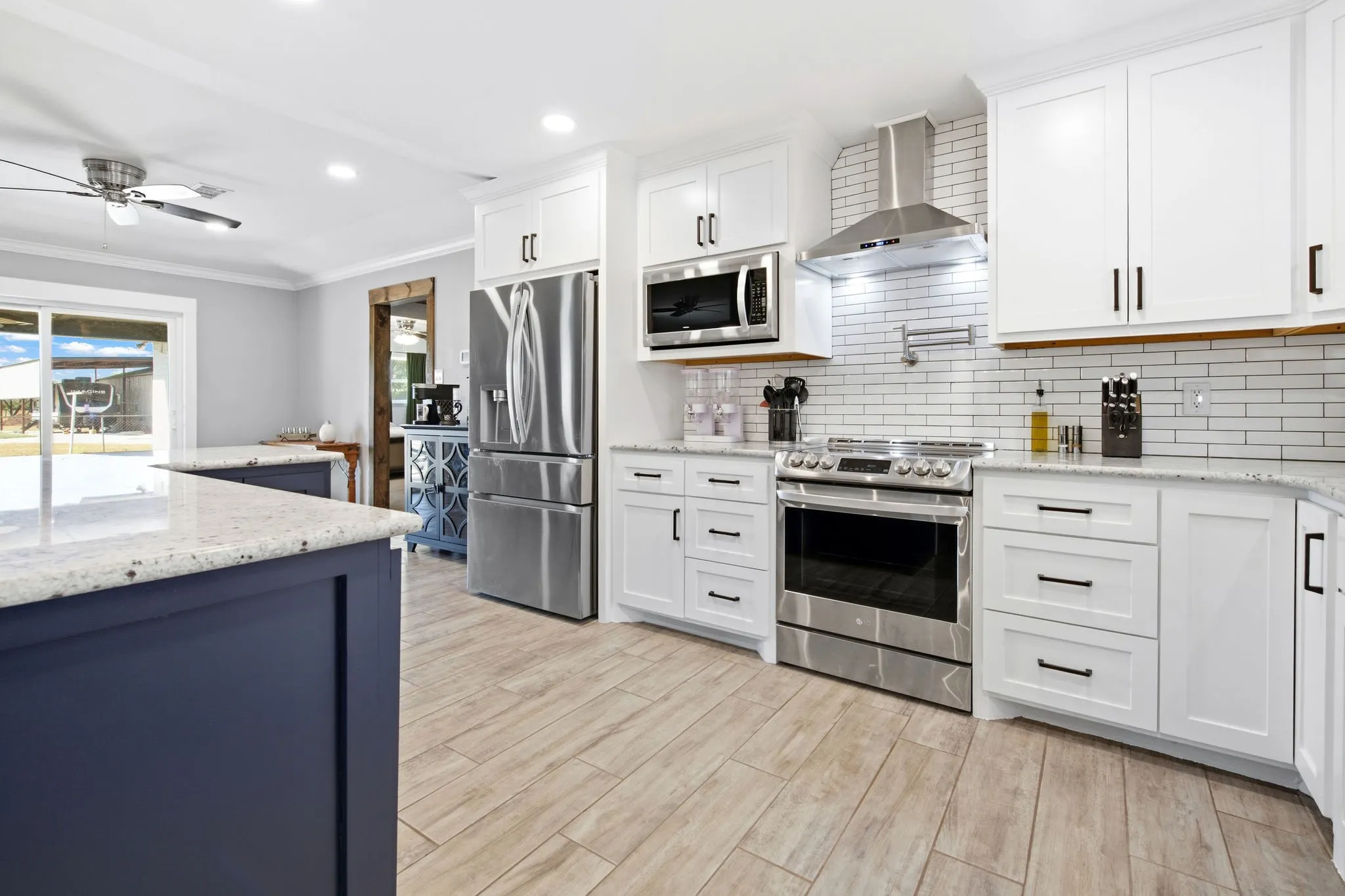 Contemporary kitchen featuring white cabinetry, stainless steel appliances, a subway tile backsplash, light wood-finish flooring