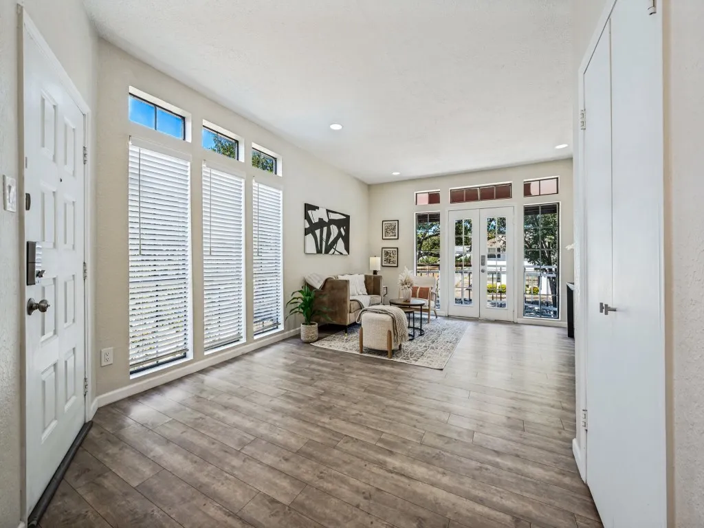 Vaulted ceiling, wood-finish flooring, white paneled entry door, built-in storage, and French doors to the exterior