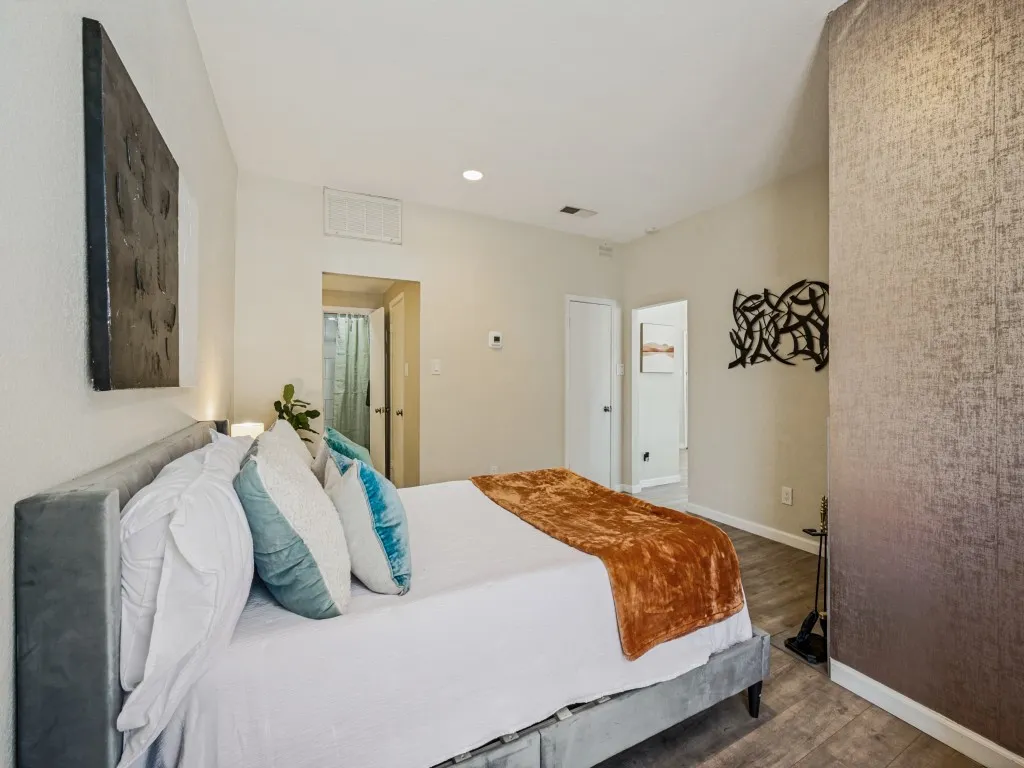 Neutral wall paint, vaulted ceiling, recessed lighting, wood-finish flooring, and a textured accent wall