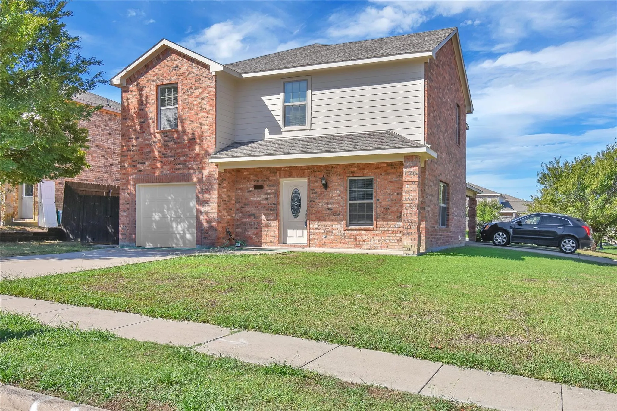 Brick and siding exterior with a covered entry, attached garage, and concrete driveway