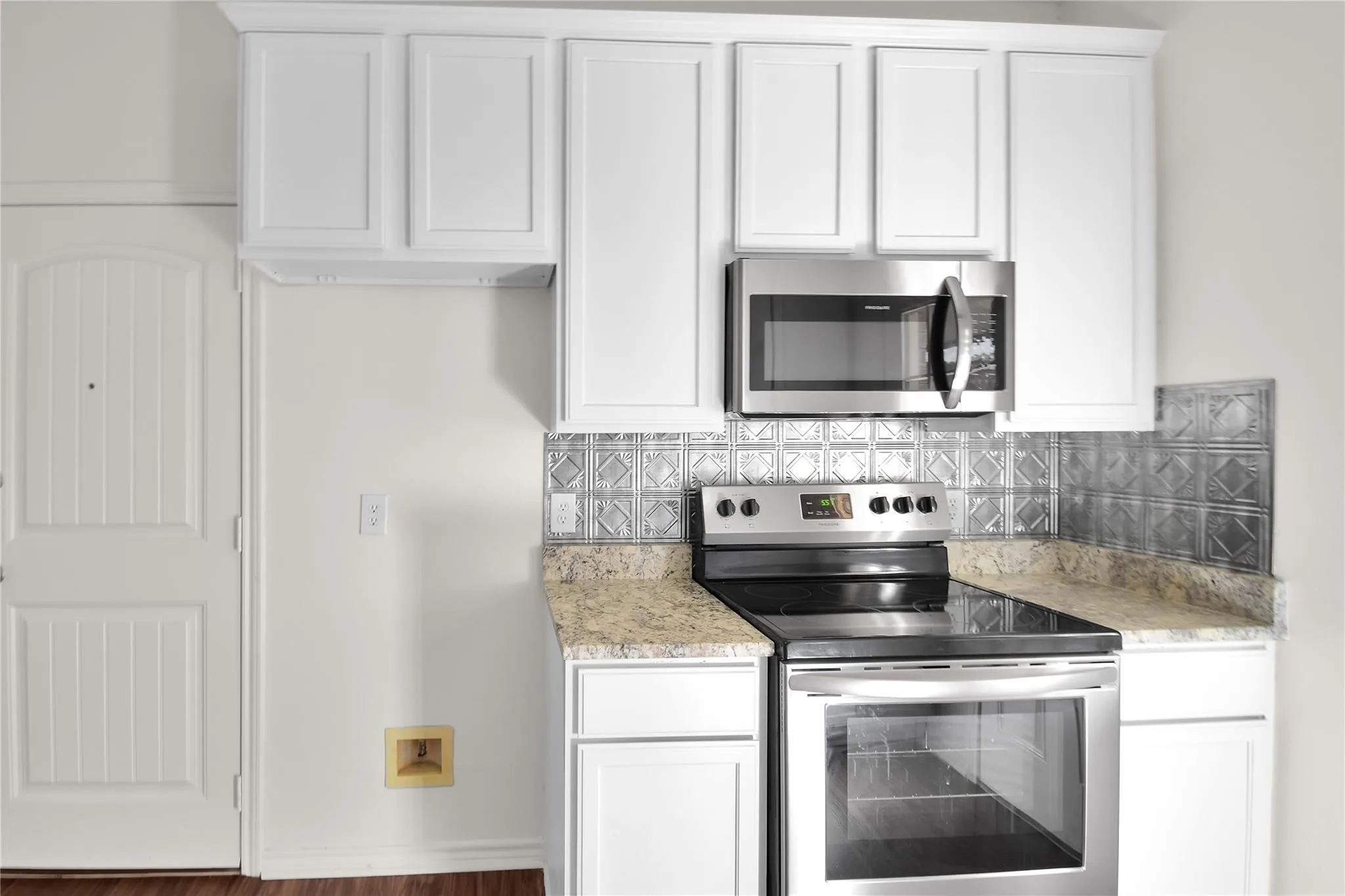White paneled cabinetry with stainless steel appliances, granite-style countertops, and a decorative tile backsplash