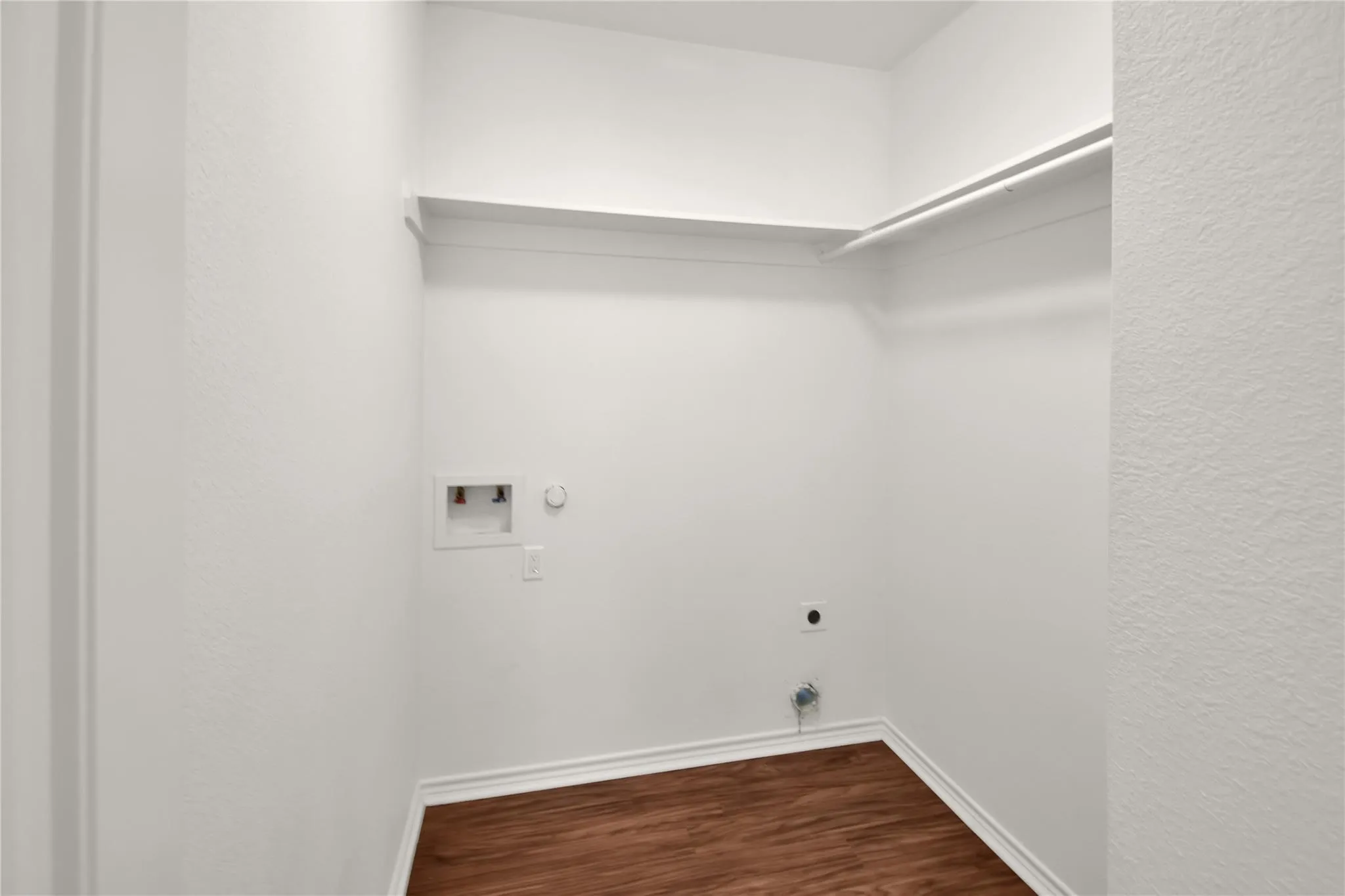 Utility closet with wood-finish flooring, white baseboards, and built-in shelving