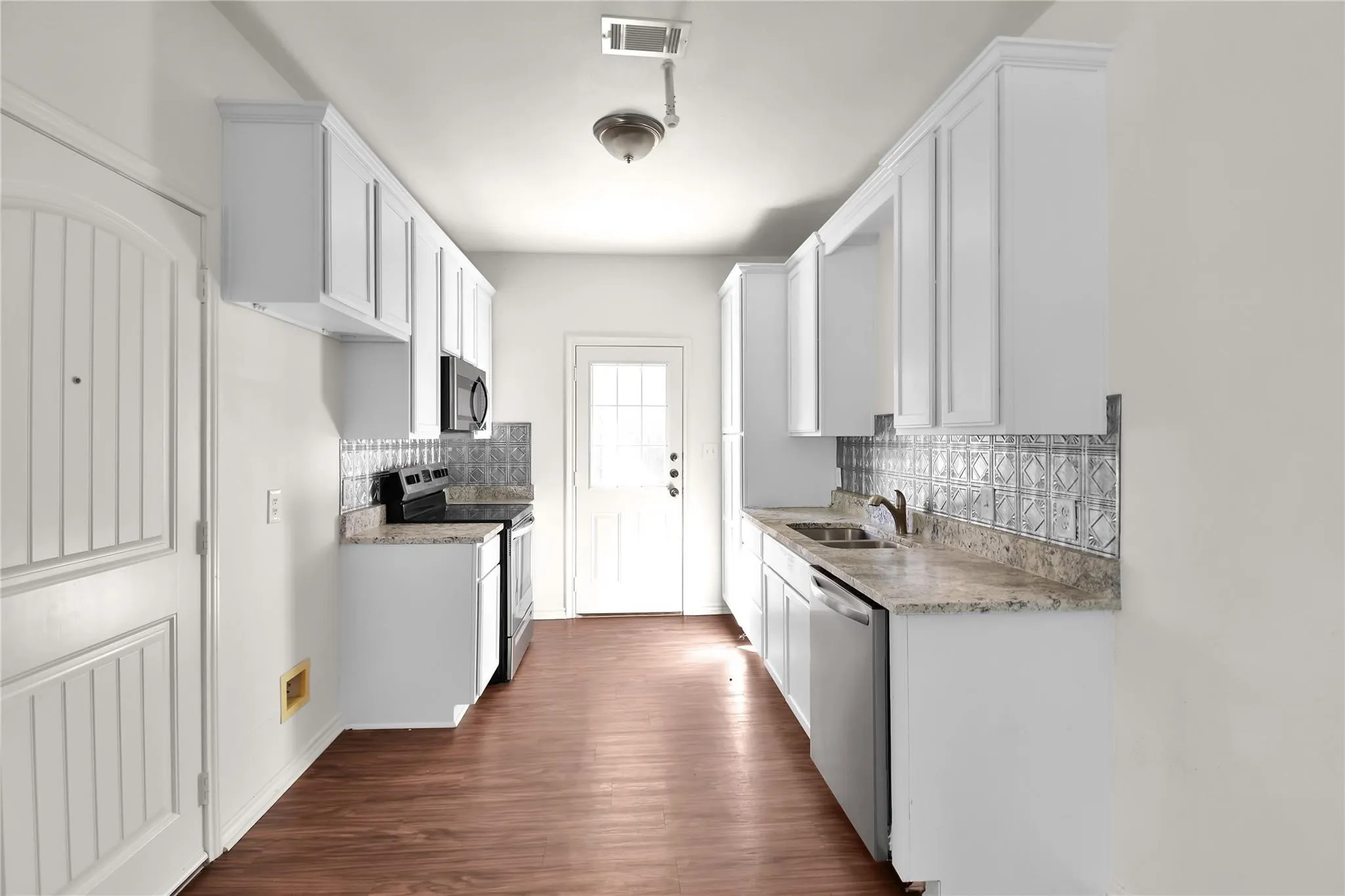 Kitchen featuring white cabinetry, wood-finish flooring, light-toned countertops, and a patterned backsplash