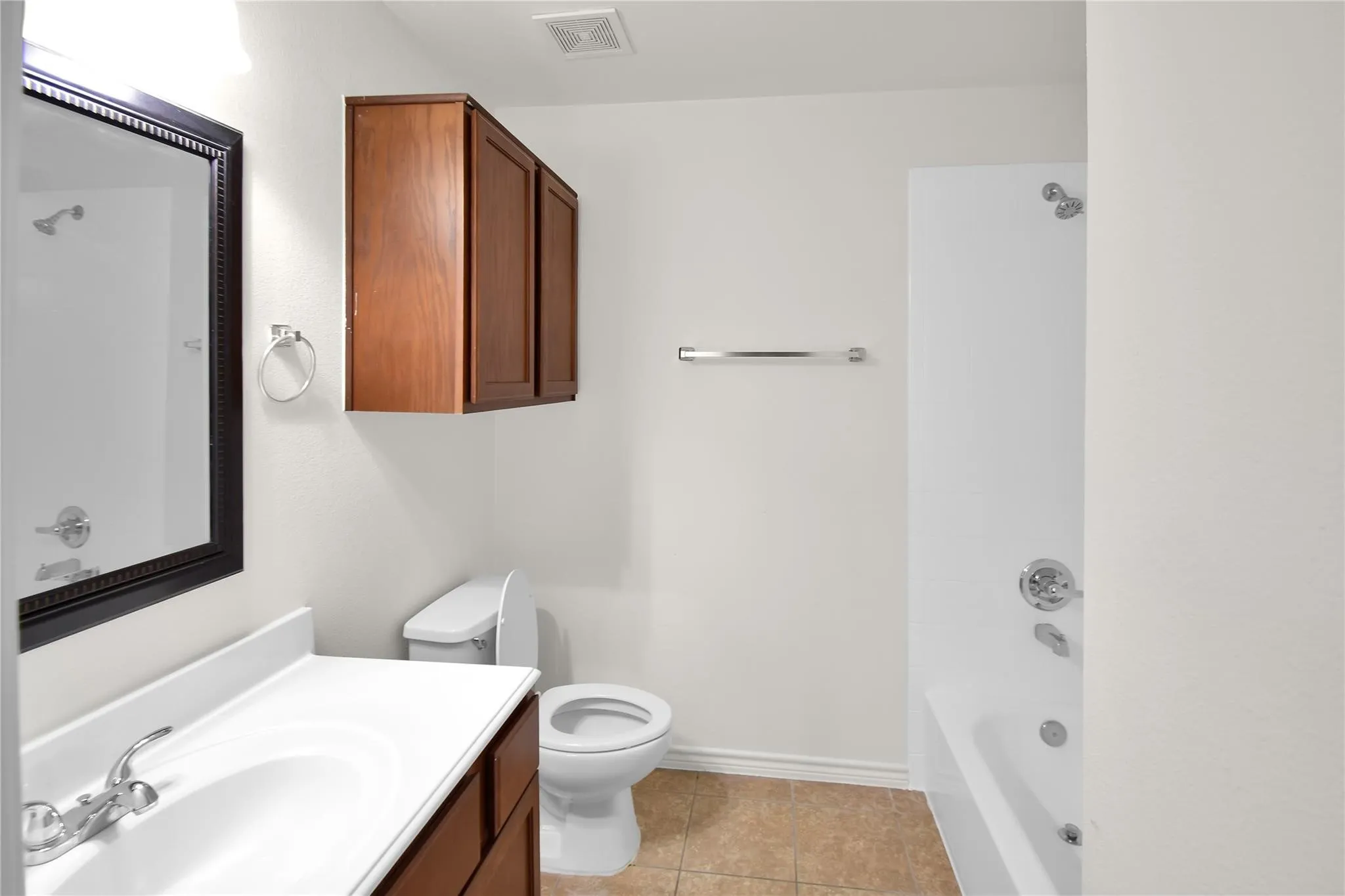 Bathroom featuring a wood-finish vanity with a white countertop, wall-mounted wood-finish cabinetry, a white toilet, and a white tub with shower
