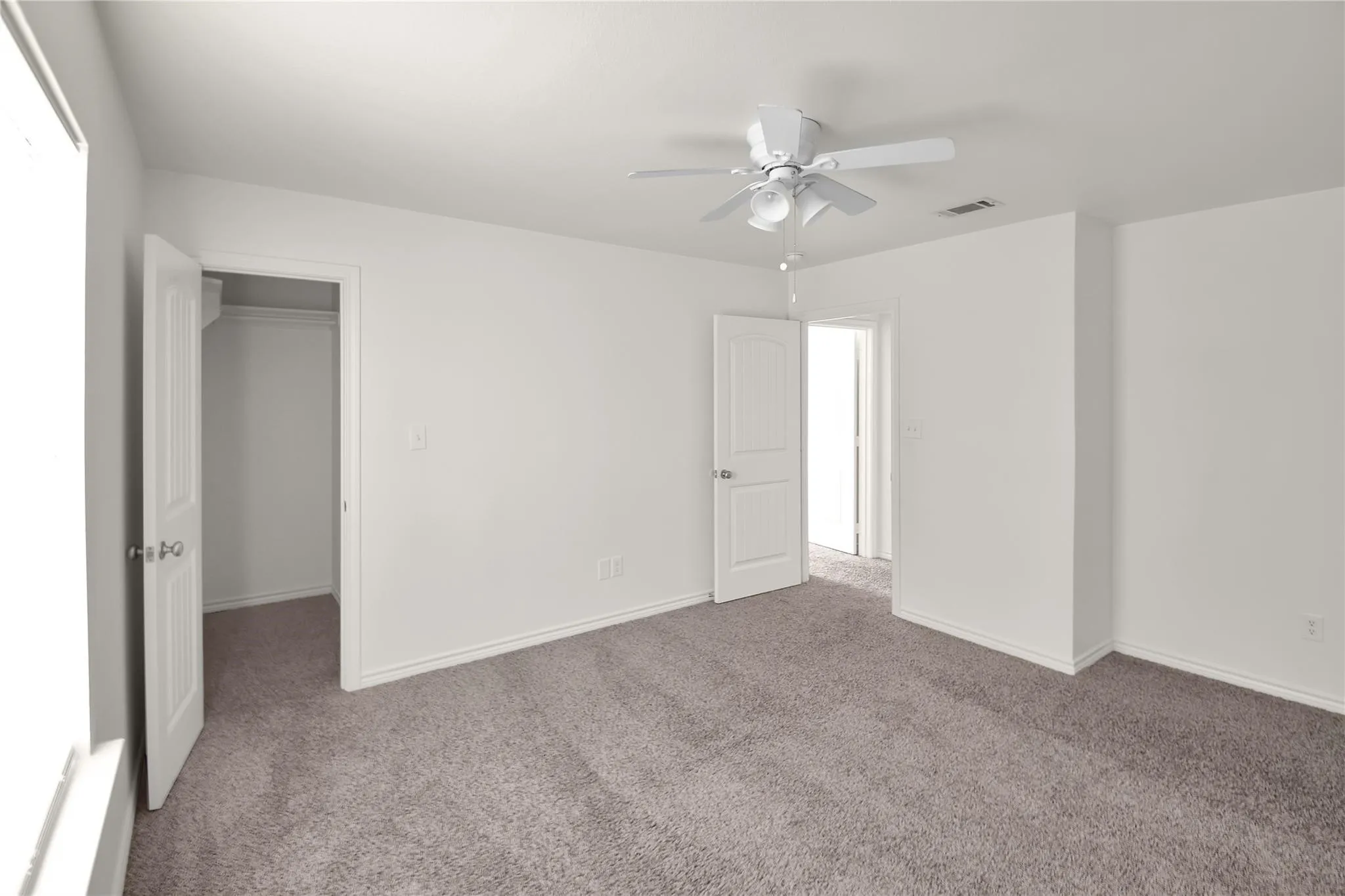Neutral tone walls, grey carpet flooring, white trim, and a ceiling fan with integrated lighting