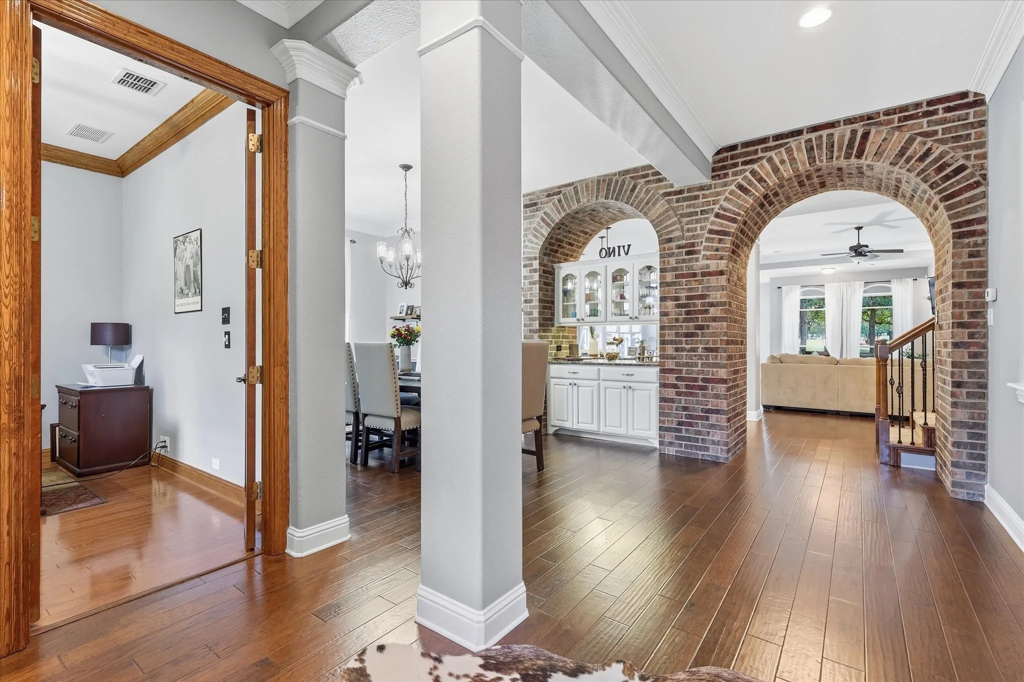 This is the kind of entrance buyers remember — dramatic brick archways, soaring architectural detail, and gorgeous hardwood floors create instant character.