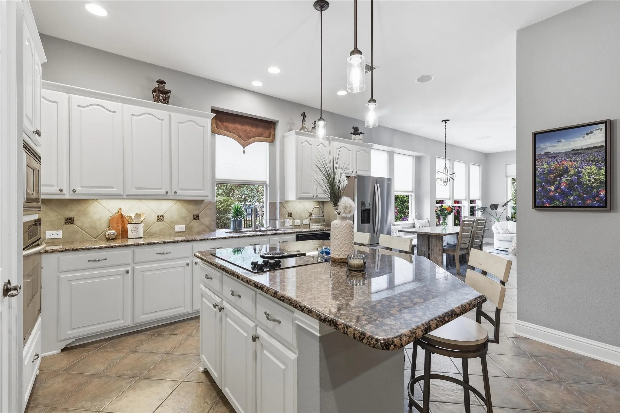 A bright, spacious kitchen with crisp white cabinetry, granite countertops, abundant storage, and a large center island ready for everything from morning coffee to entertaining.