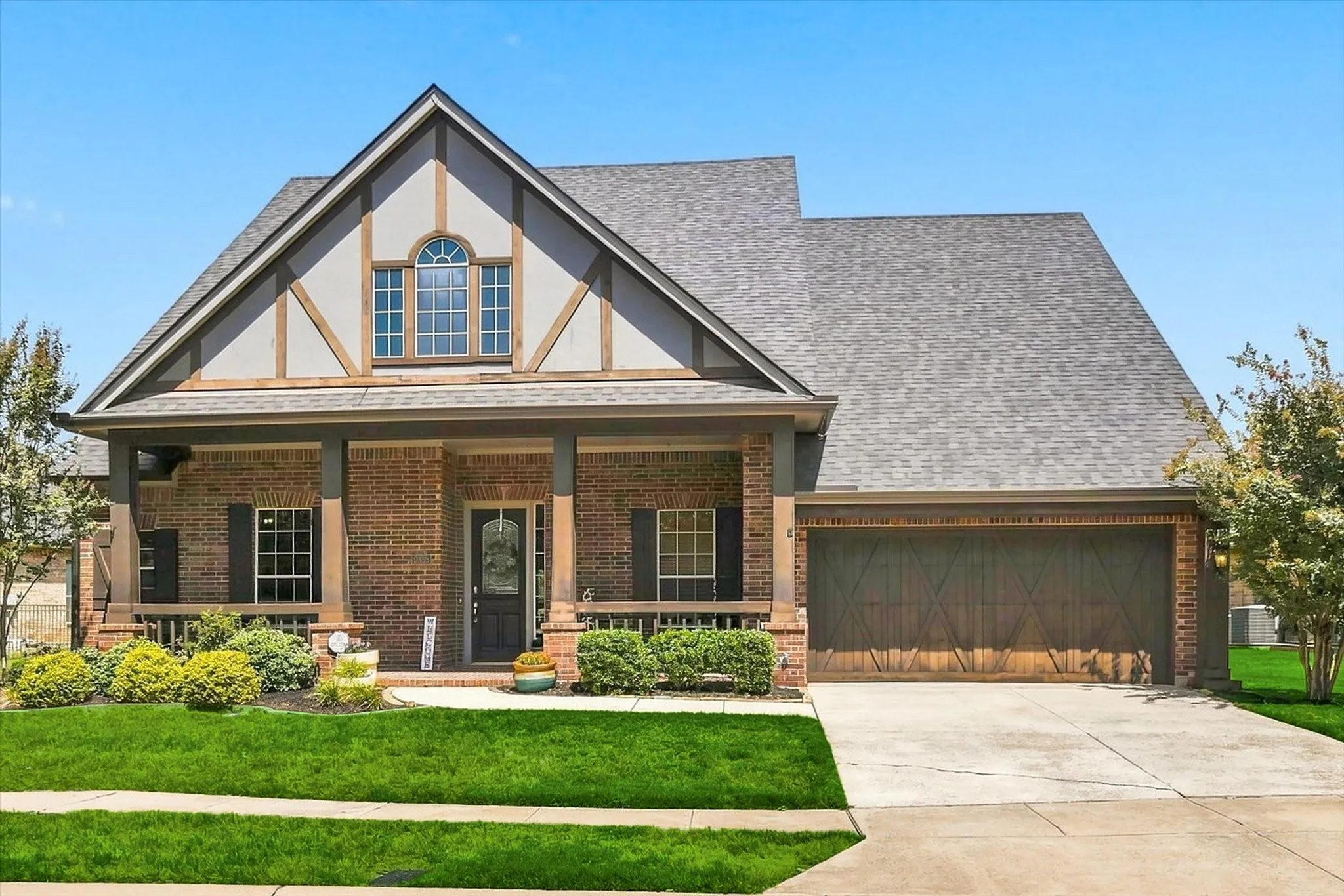 A striking first impression with warm brick, Tudor-inspired detailing, an inviting covered porch, and a beautifully finished garage.