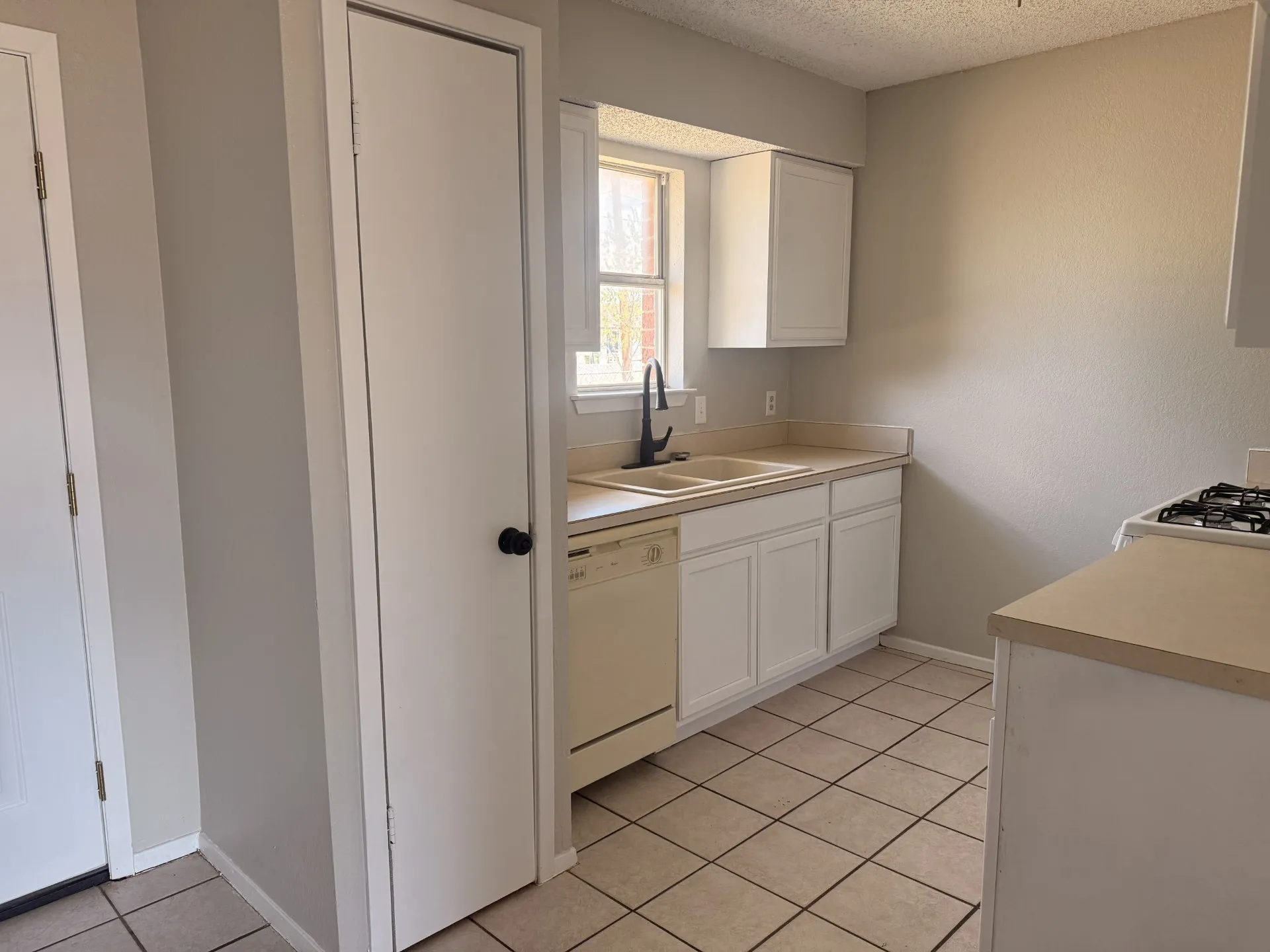 Kitchen featuring white cabinetry, a double basin sink with a dark faucet, and a gas range