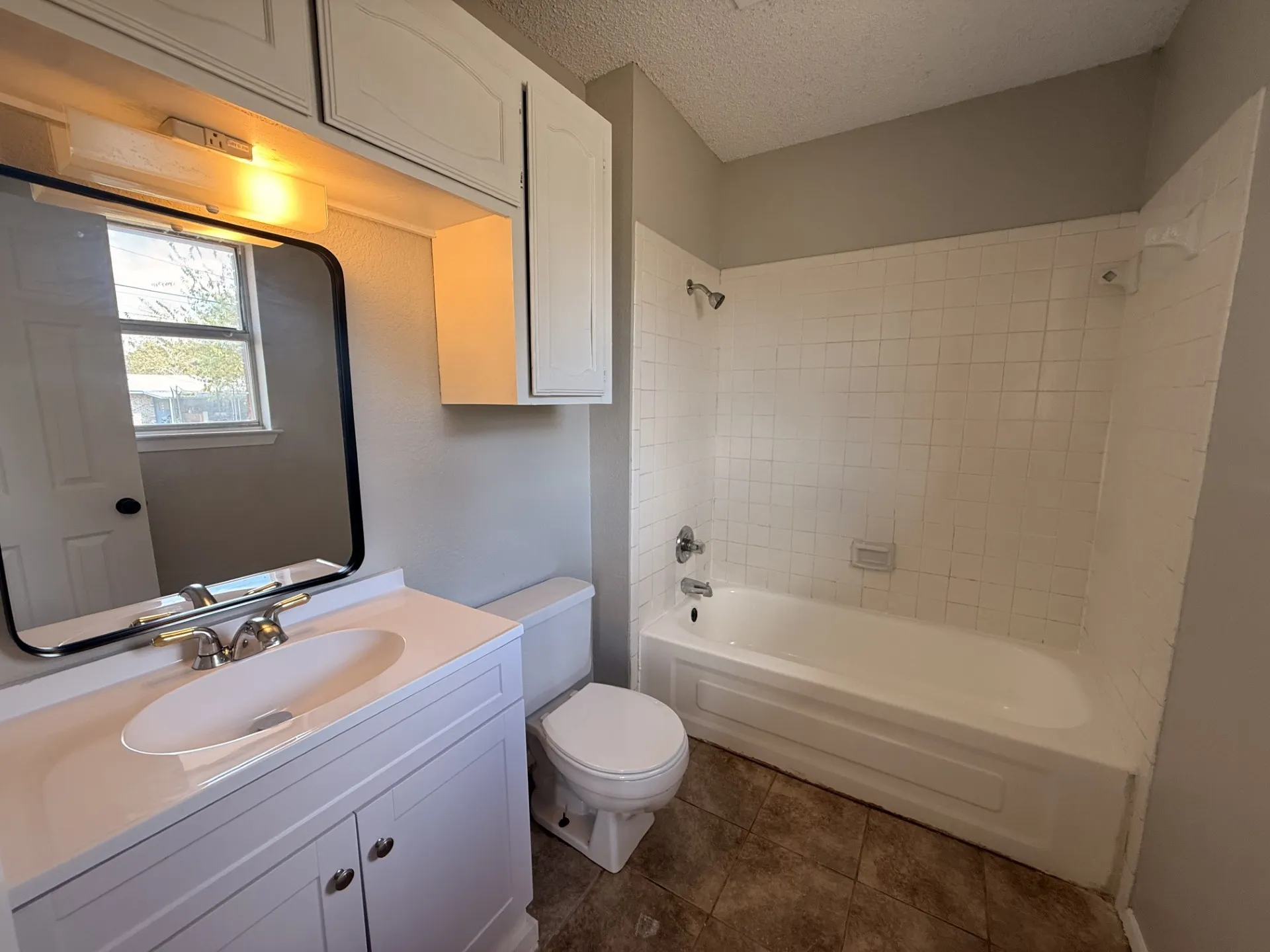 White vanity with an integrated sink, built-in medicine cabinet, and overhead lighting