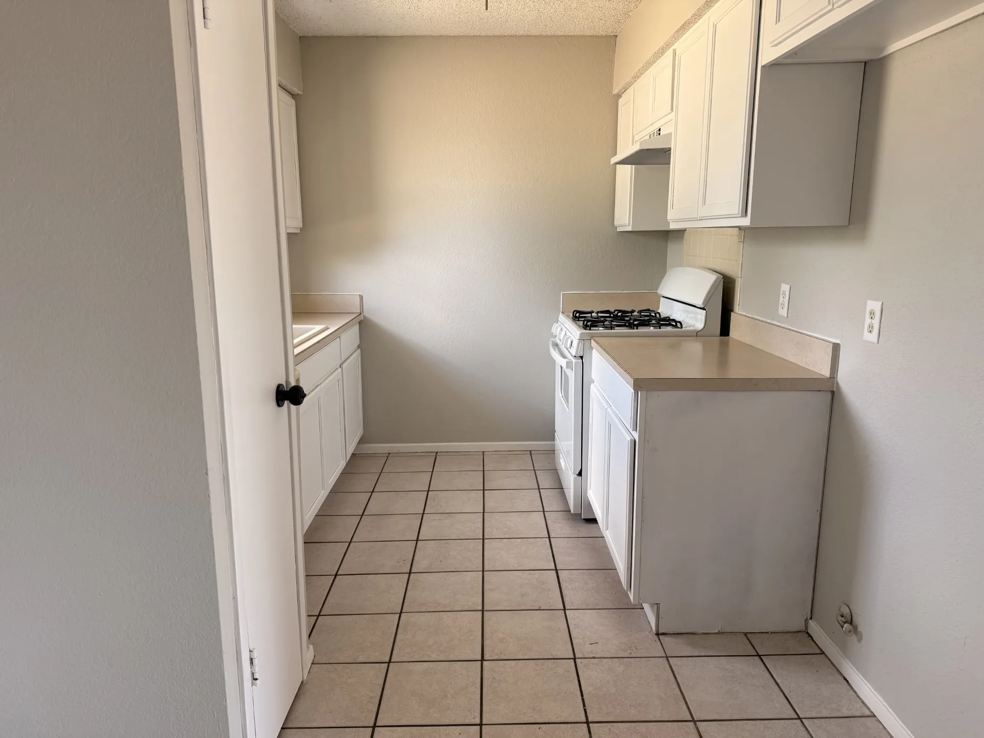 Kitchen with white cabinetry, a built-in range, and tile flooring