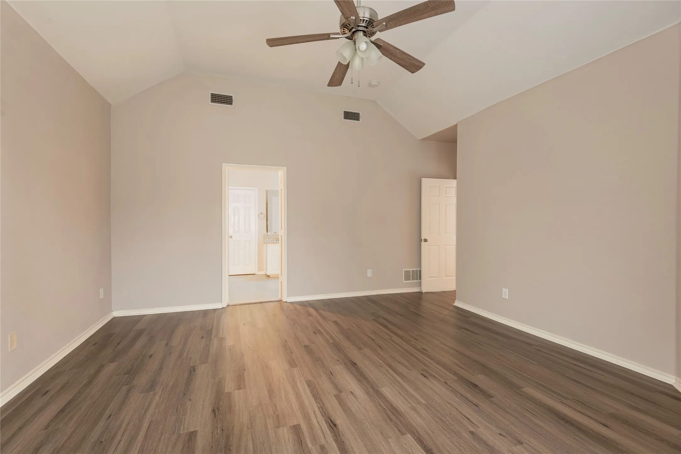 Empty room featuring ceiling fan, dark hardwood / wood-style flooring, and vaulted ceiling