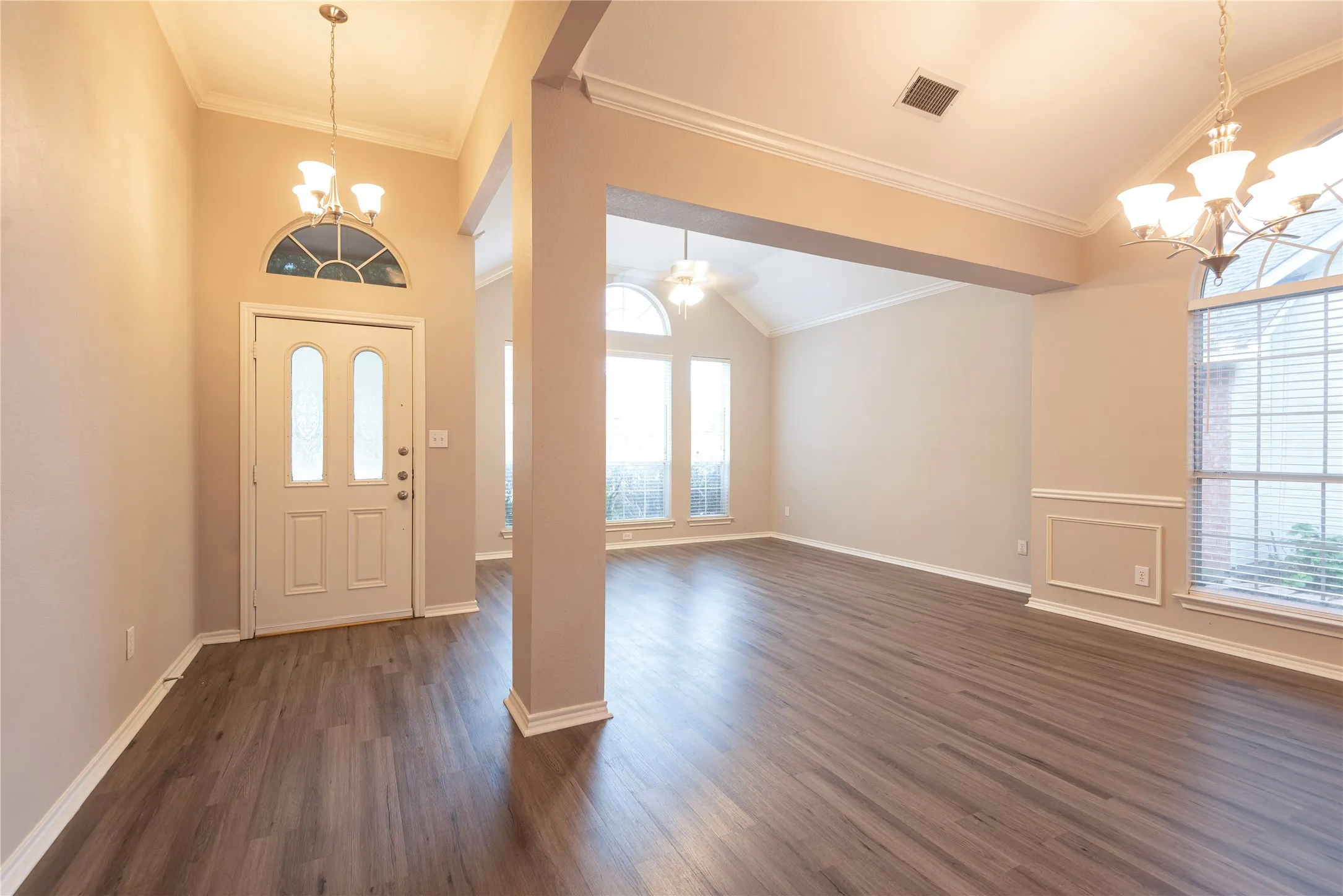 Entryway featuring ceiling fan with notable chandelier, crown molding, and dark wood-type flooring