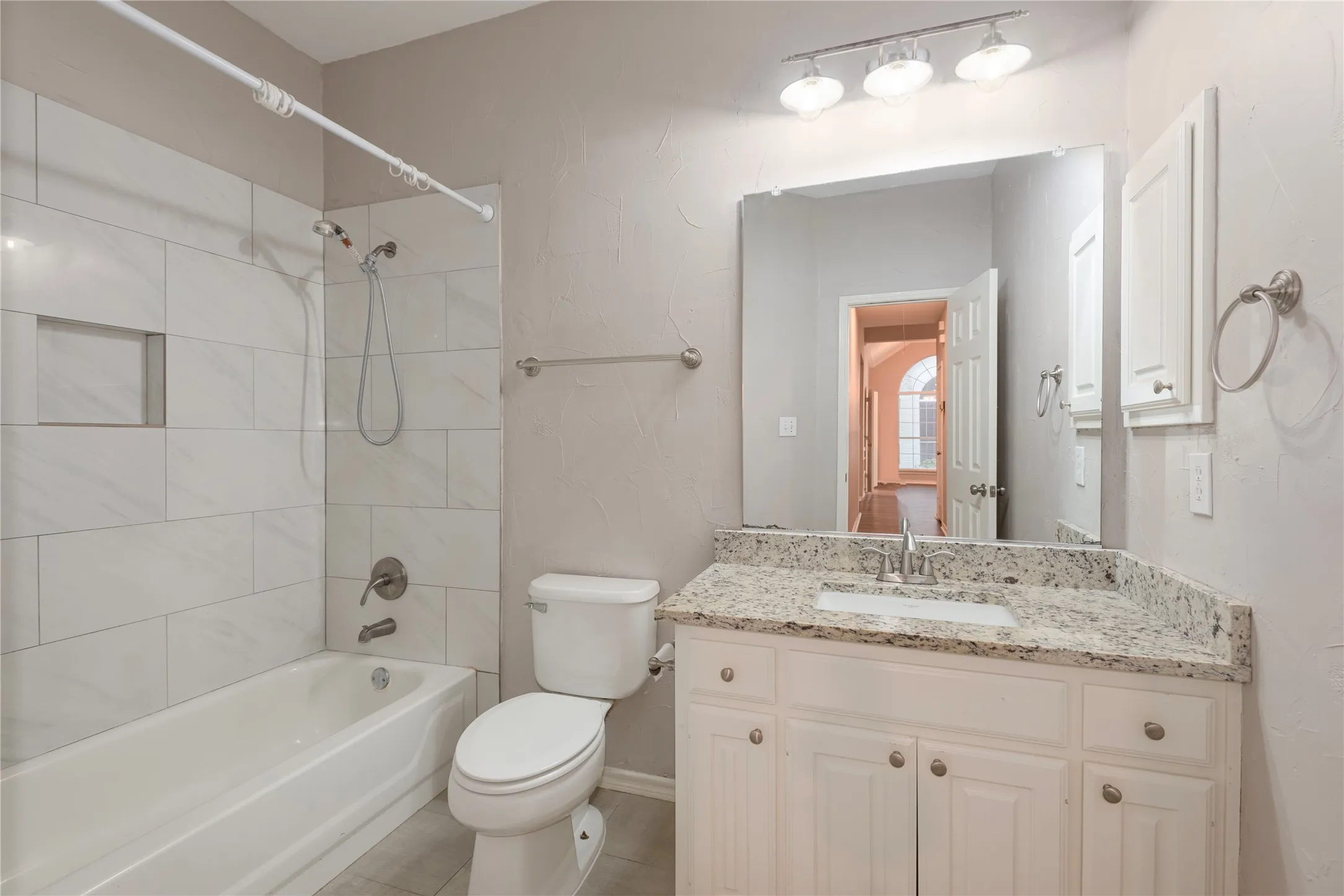 Full bathroom featuring tile patterned flooring, tiled shower / bath combo, toilet, and vanity