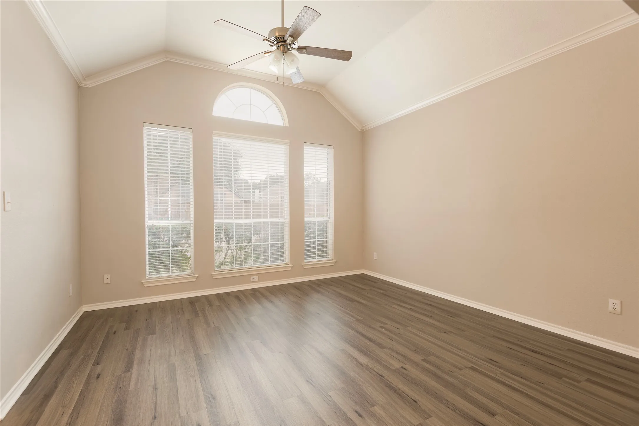 Spare room with lofted ceiling, crown molding, and dark wood-type flooring
