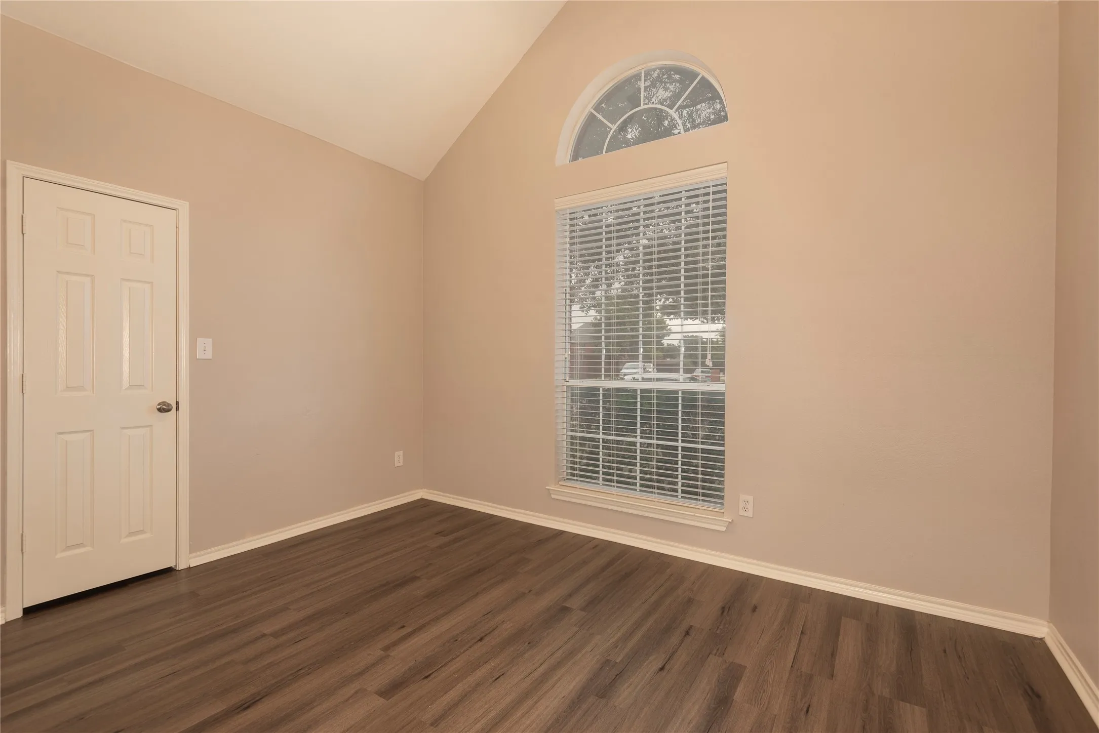 Spare room with dark hardwood / wood-style floors and high vaulted ceiling