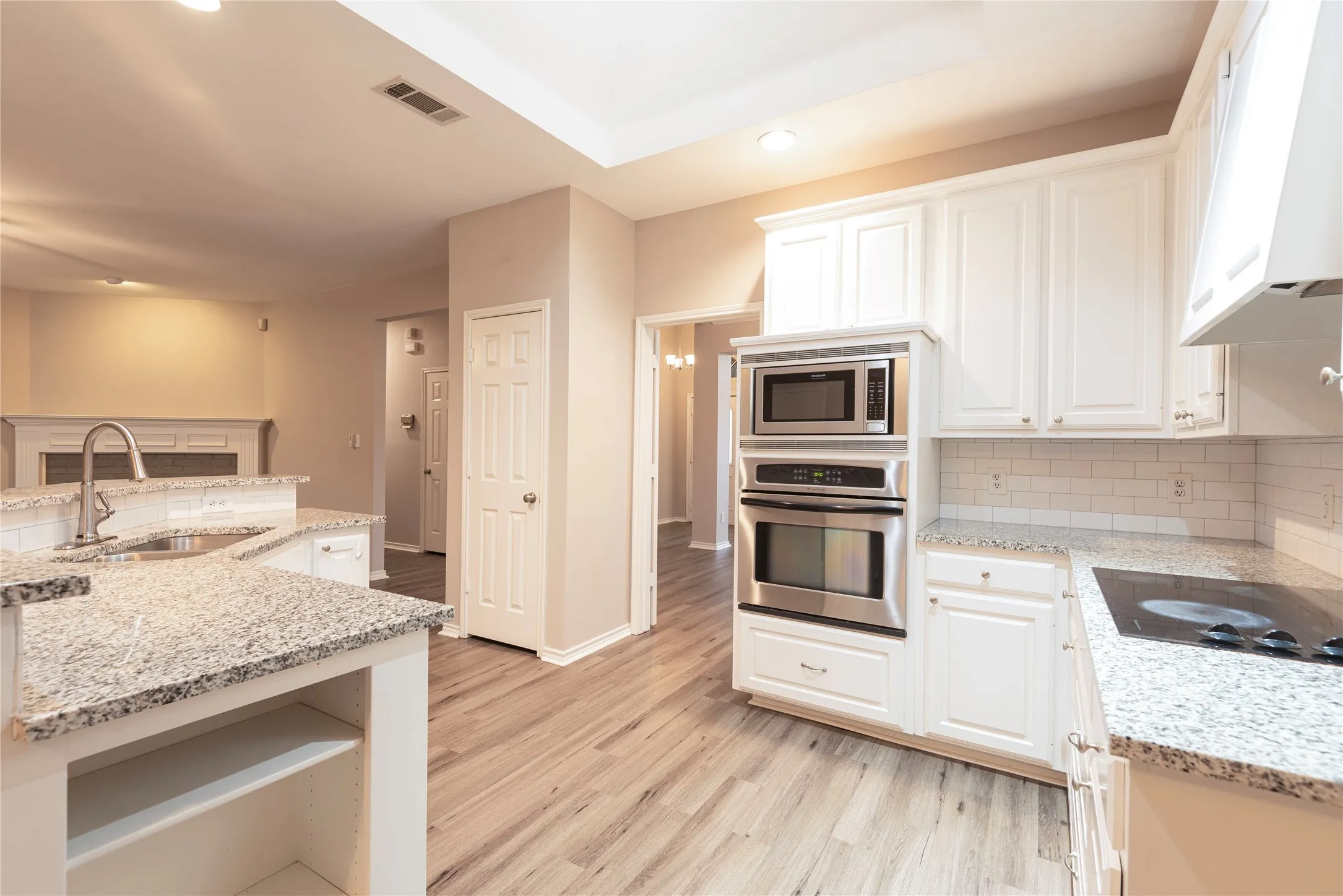 Kitchen featuring light stone countertops, sink, stainless steel appliances, extractor fan, and white cabinets