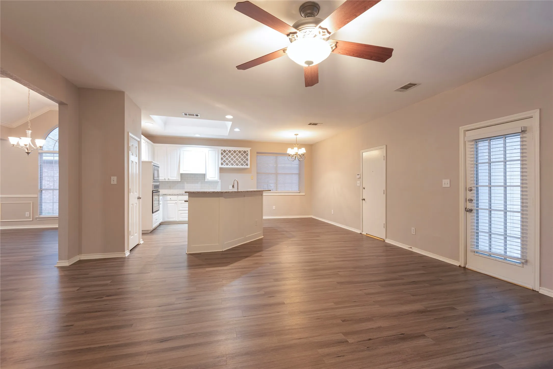 Kitchen featuring a skylight, a kitchen island, decorative light fixtures, dark hardwood / wood-style floors, and white cabinetry