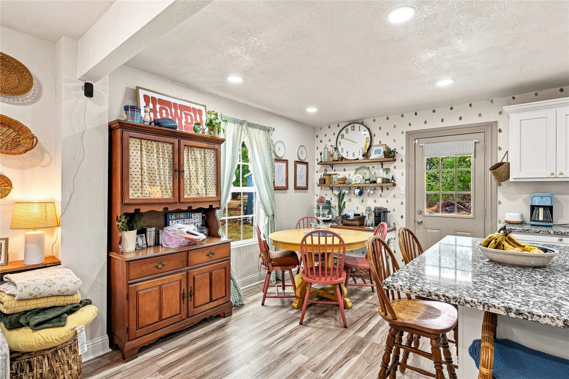 Wood-finish flooring throughout, recessed ceiling lighting, a rear entry door with integrated window, white upper cabinetry, and a granite-finish countertop