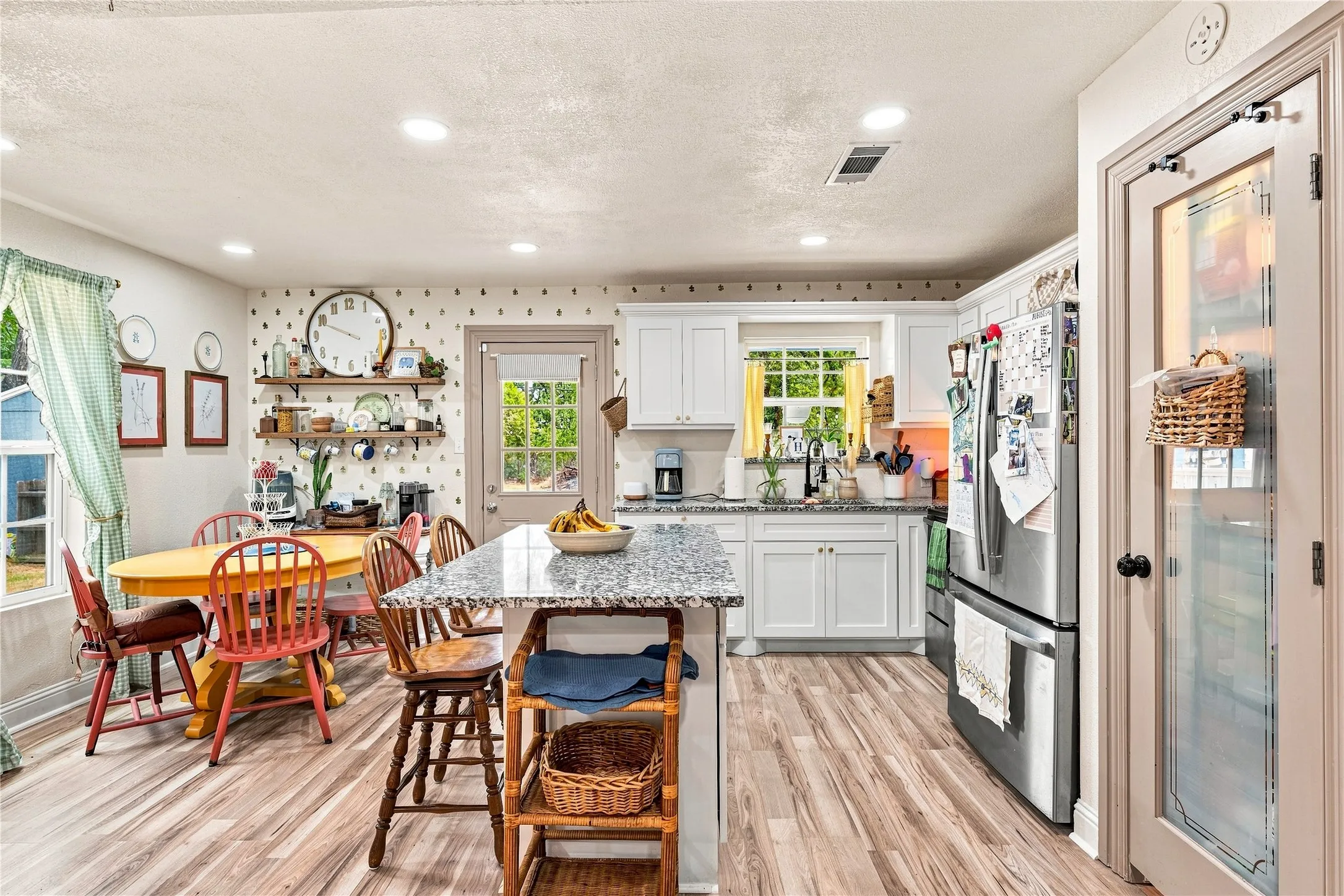 Kitchen featuring wood-finish flooring, white cabinetry, a center island with a stone-finish countertop, and stainless steel appliances