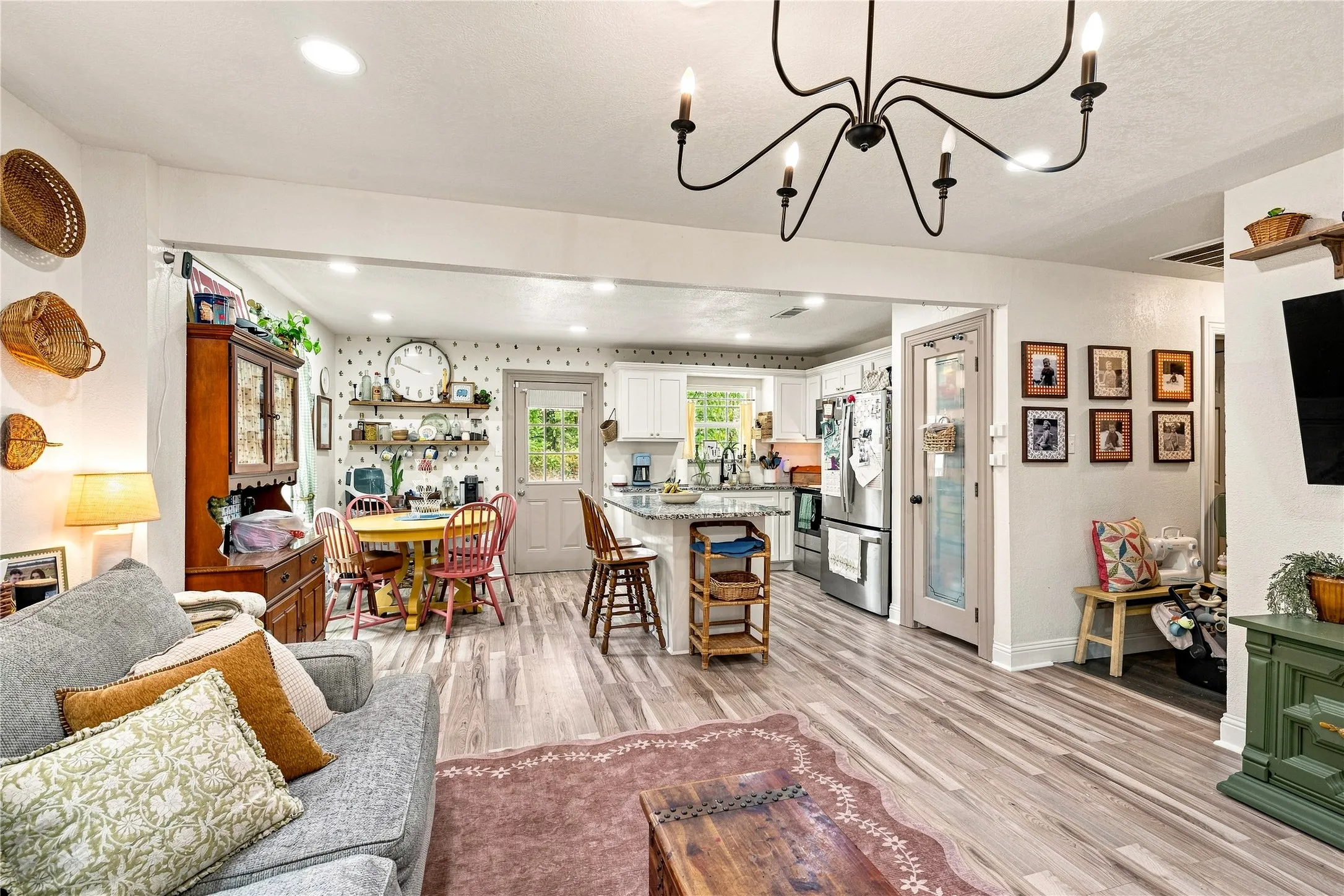 Open-concept living area featuring wood-finish flooring, recessed lighting, and a kitchen with white cabinetry