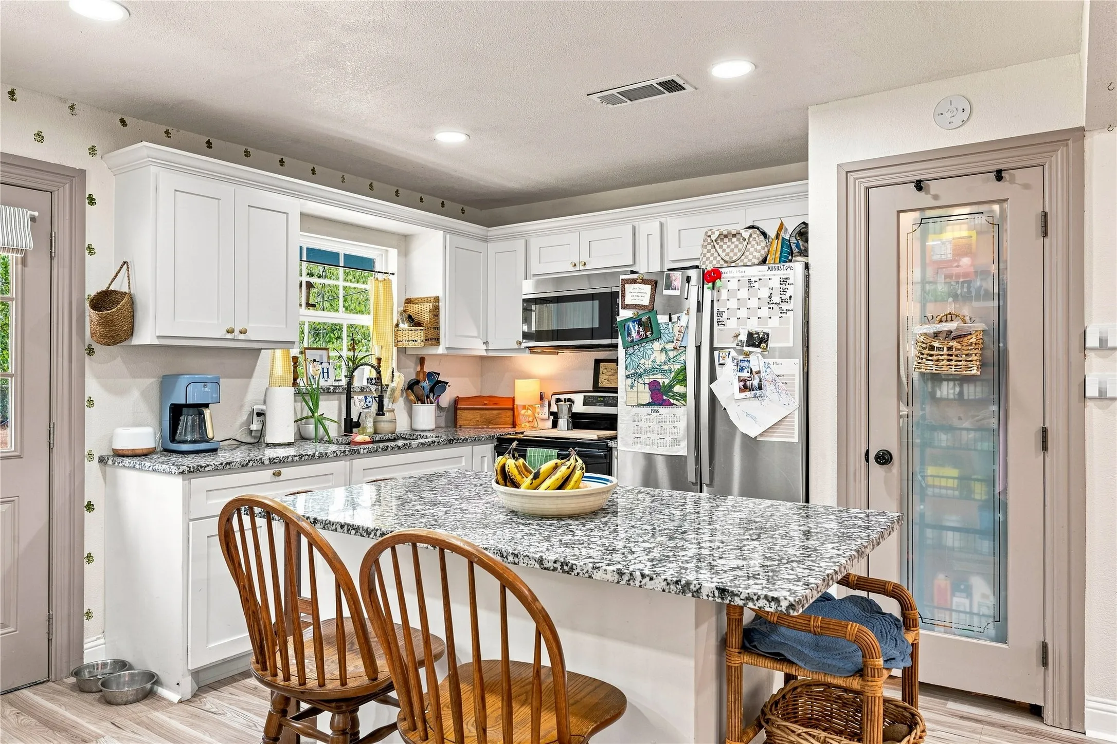 White shaker cabinetry, granite countertops, stainless steel appliances, recessed lighting, and a glass-paneled pantry door