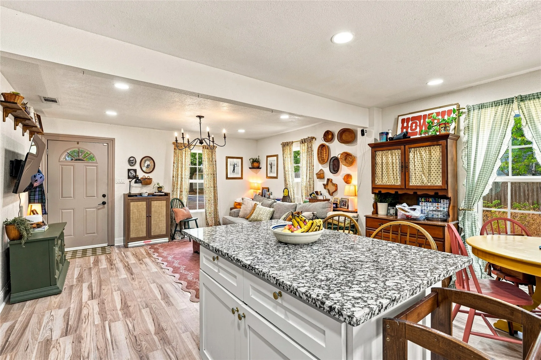Kitchen island with granite countertop, recessed lighting, wood-finish flooring, and a chandelier in the living area