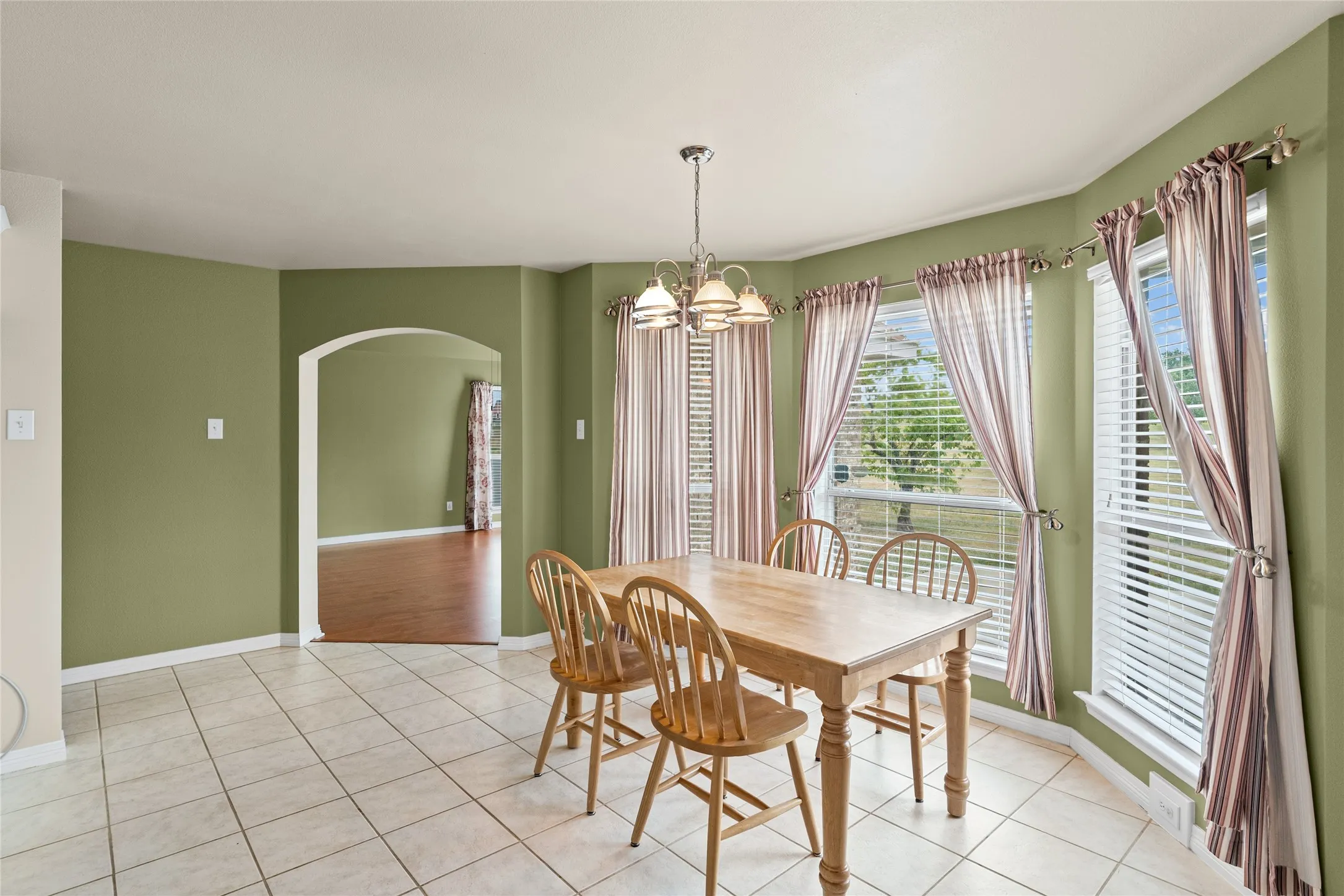 Tiled flooring, multiple windows, an arched doorway, and an overhead light fixture