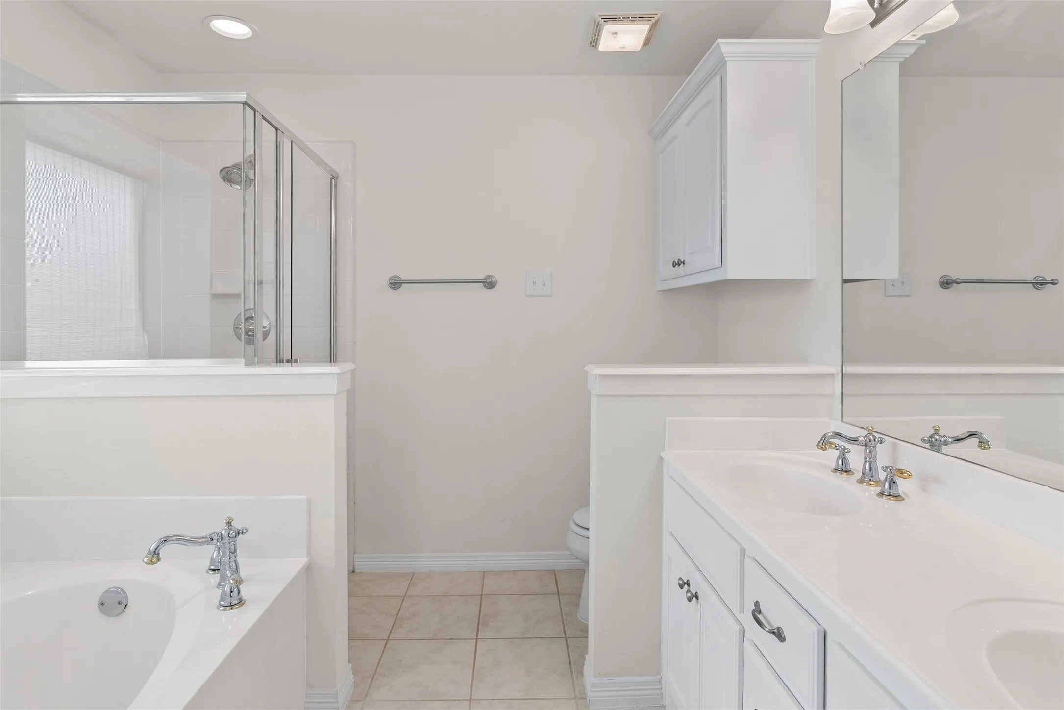 Dual vanity with integrated sinks, chrome fixtures, built-in cabinetry, and a separate shower enclosure