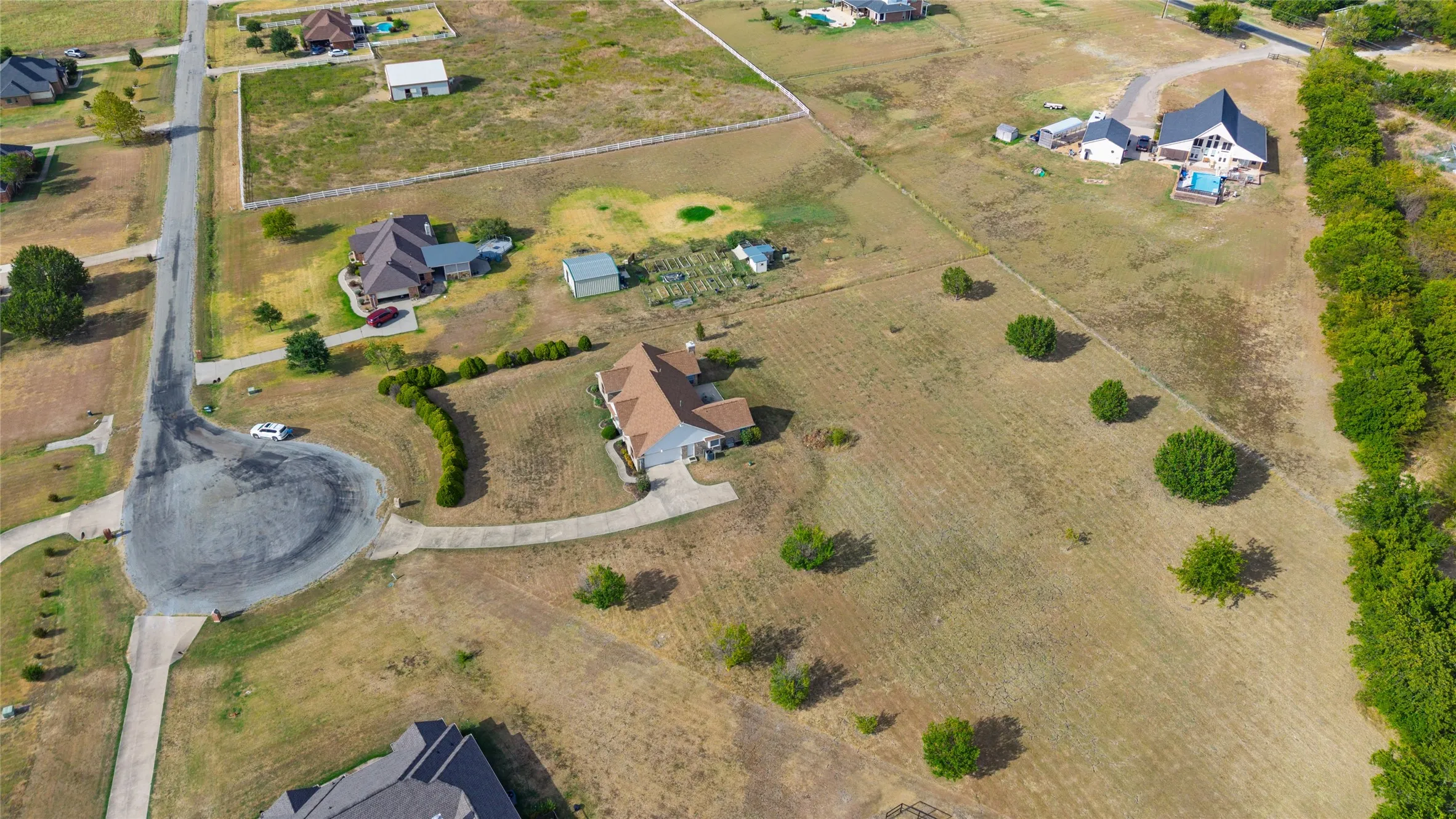 Expansive property featuring a paved cul-de-sac, mature perimeter trees, and established residences