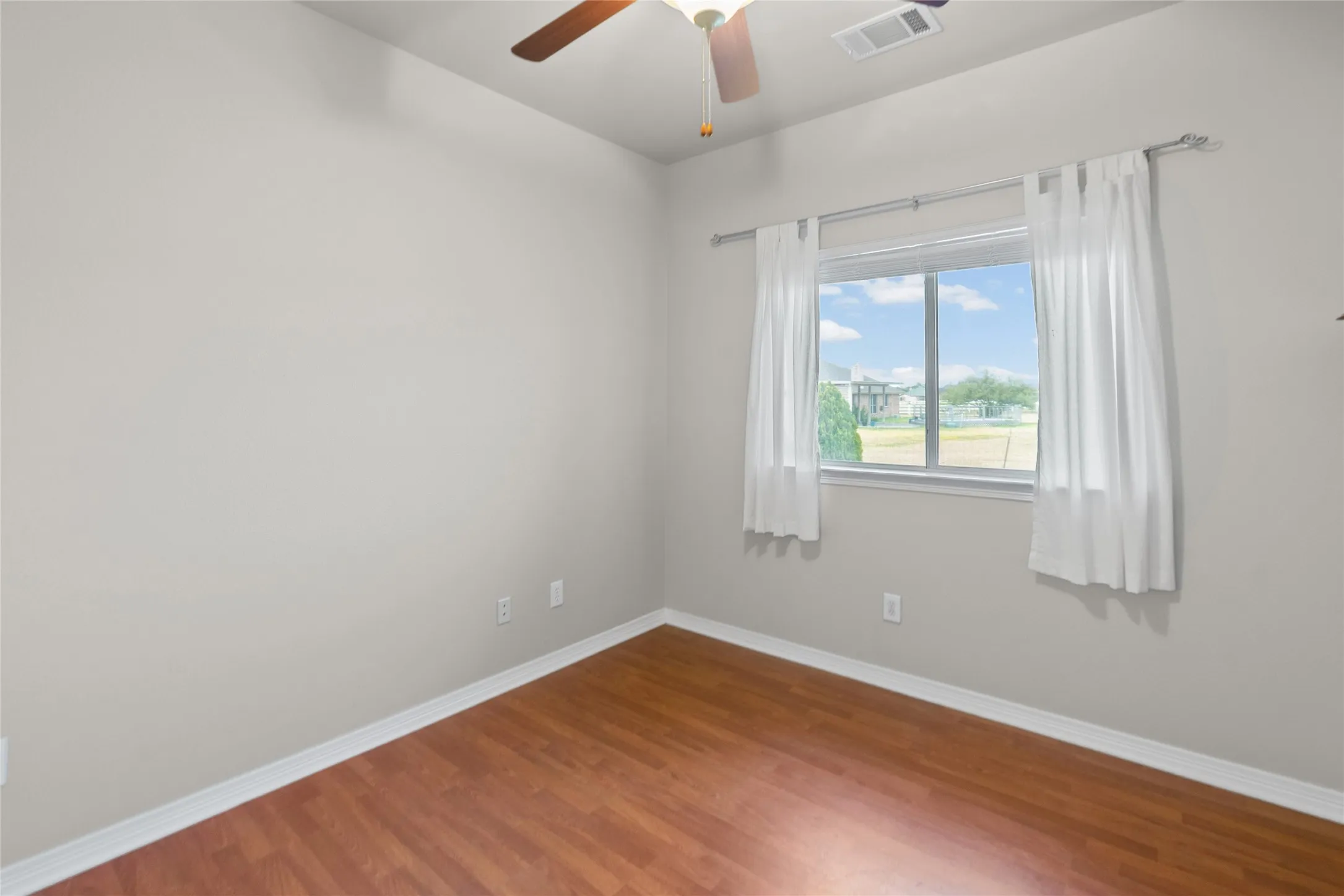 Wood-finish flooring, light gray wall tones, and a ceiling fan with integrated lighting