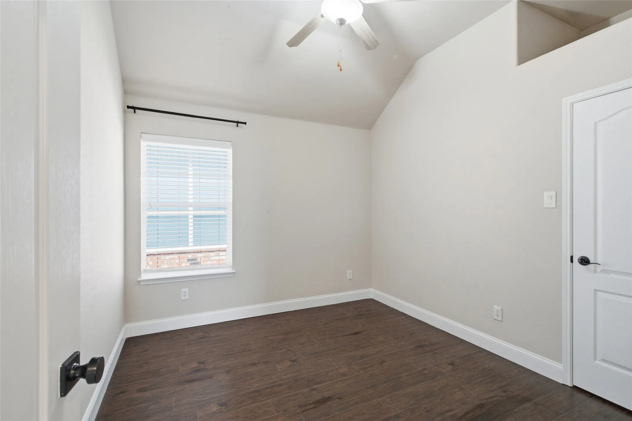Vaulted ceiling with a ceiling fan, wood-finish flooring, and a single window with blinds