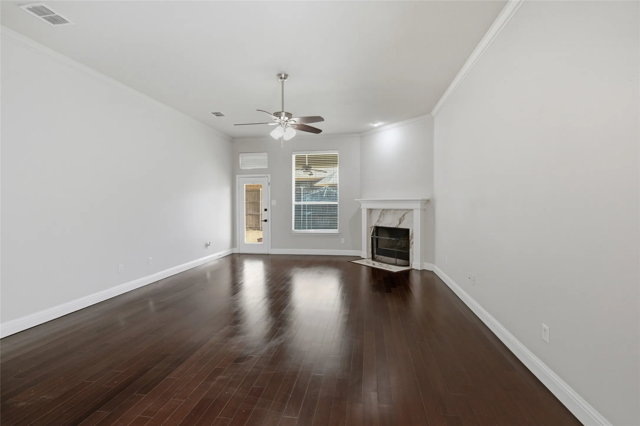 Spacious living area featuring dark wood-finish flooring and a ceiling fan