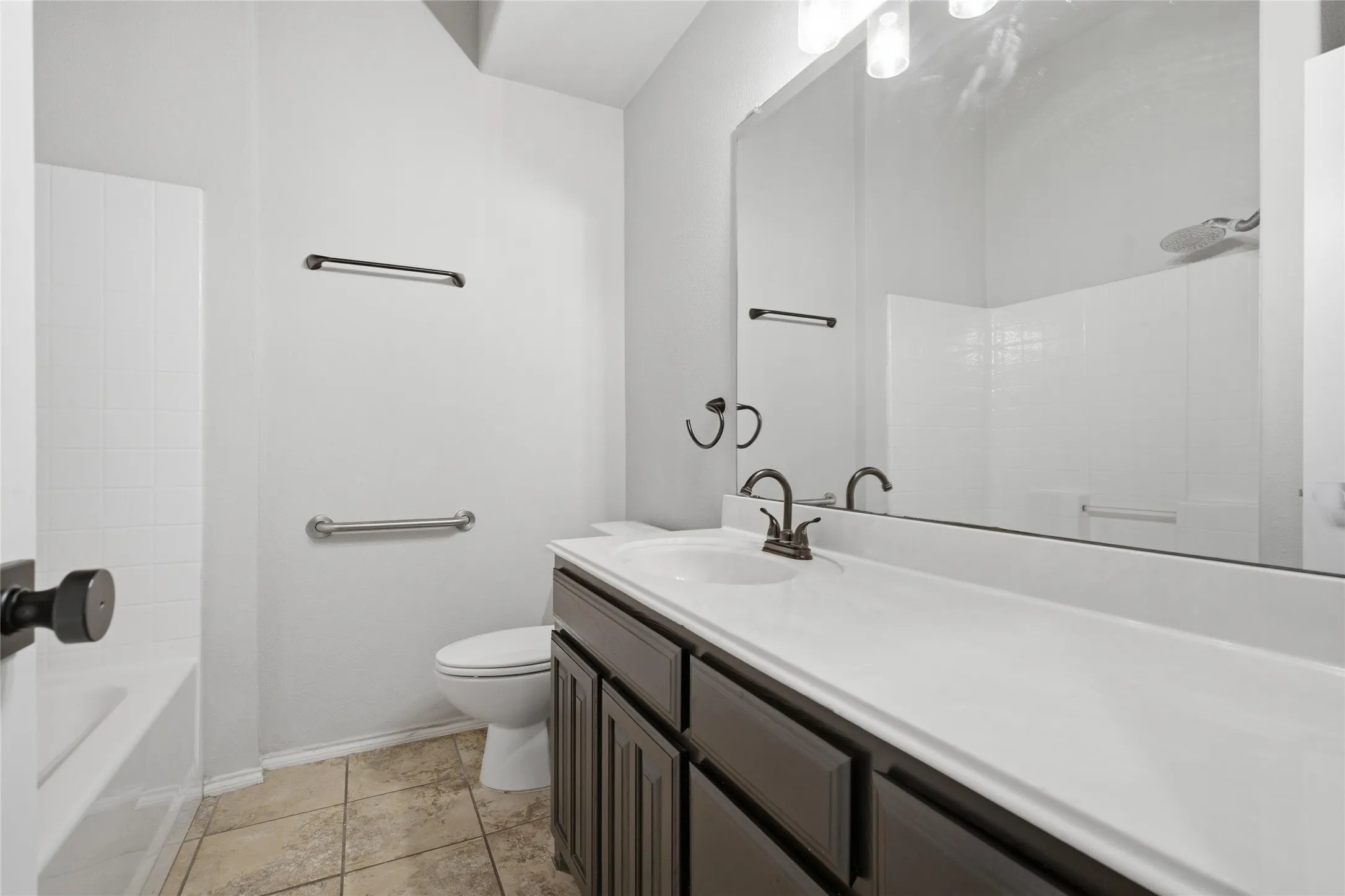 Bathroom featuring a vanity with dark wood-finish cabinetry, a large integrated sink, and a framed mirror