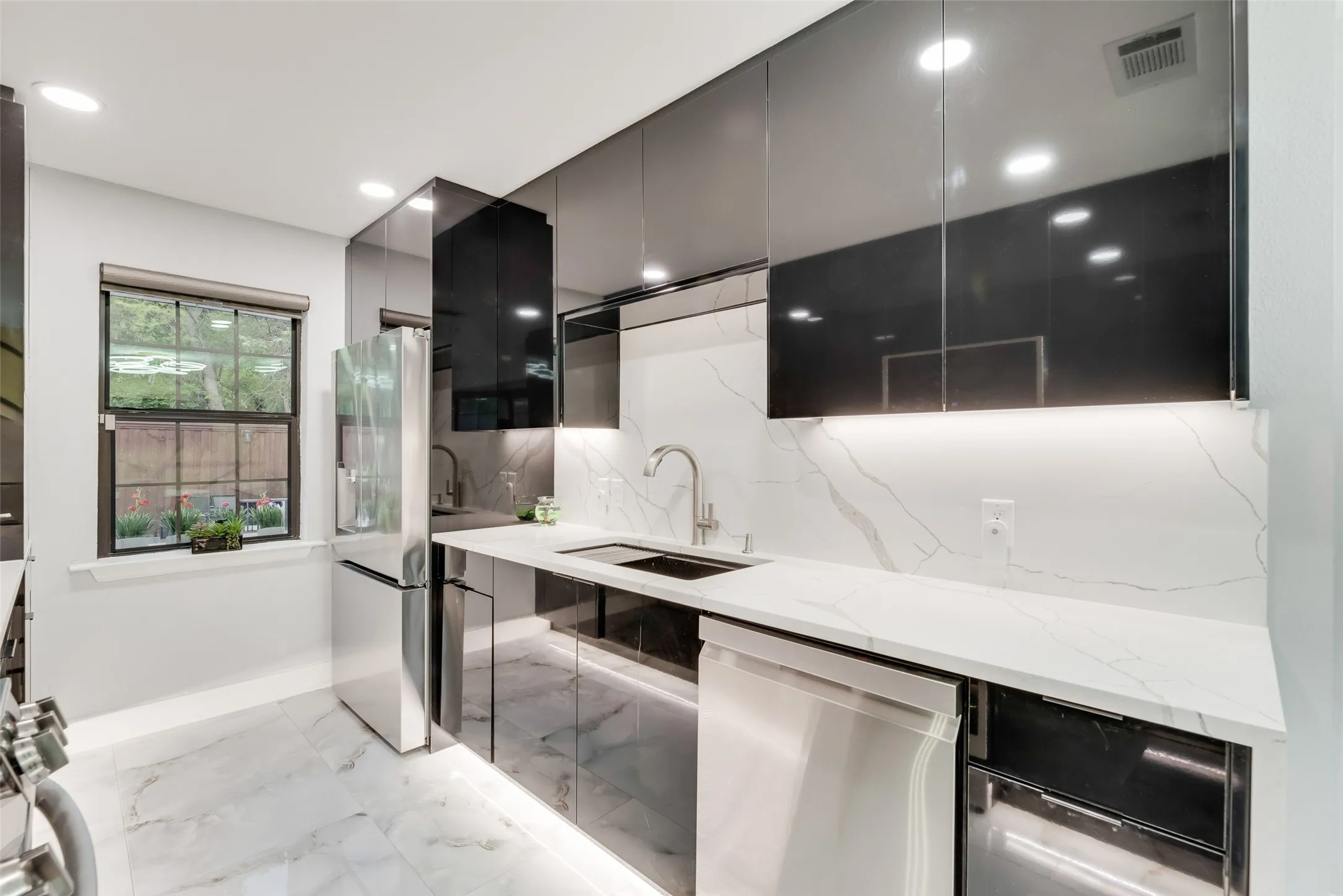 Kitchen featuring appliances with stainless steel finishes, a sink, modern cabinets, decorative backsplash, and light stone countertops