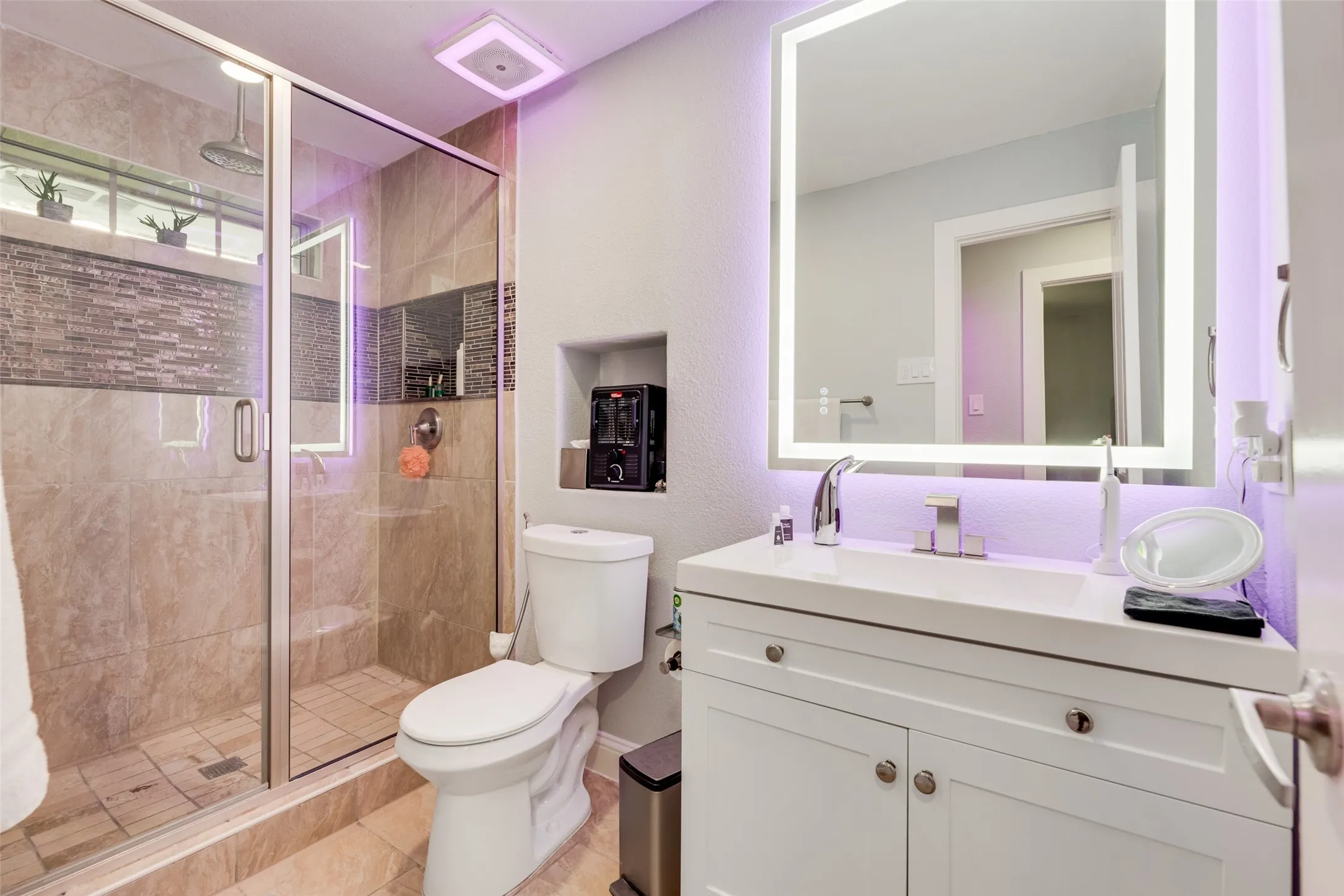 Bathroom featuring toilet, a stall shower, vanity, tile patterned floors, and baseboards